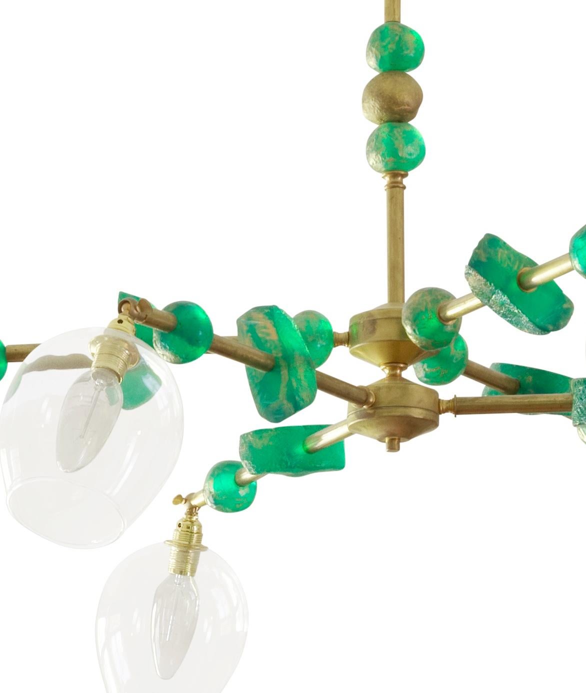 This contemporary two-tier, six-arm chandelier by Margit Wittig features sculptural components with organic and subtle textures, all cast and treated with multiple layers of patina in her London studio. The contrast of green translucent resin and