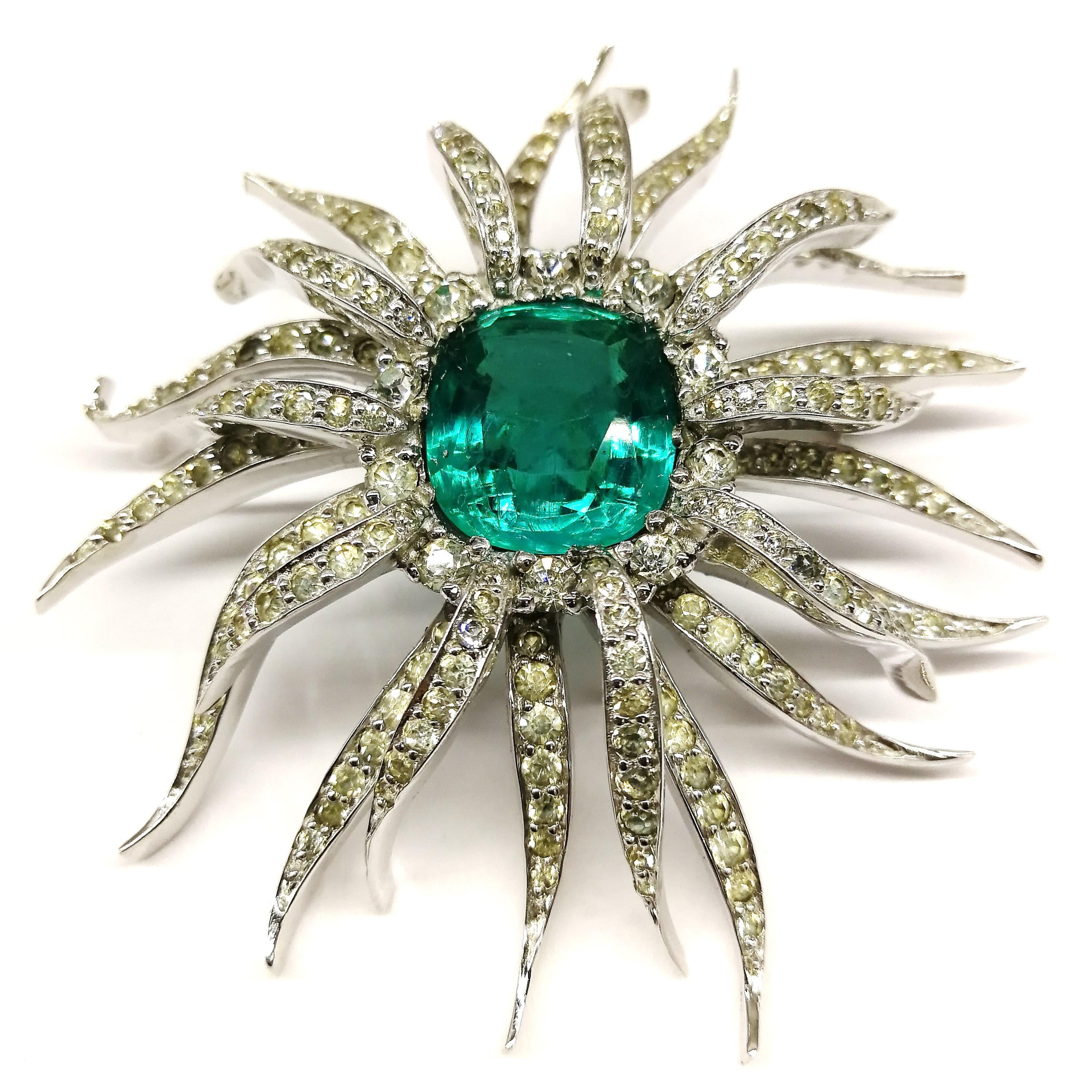 A striking and radiant 'starburst' brooch and earrings, in clear paste, with a cushion-cut 'emerald' paste stone , set in the centre of both the brooch and earrings. Also echoing a floral motif, the design captures a very real look, clean cut and