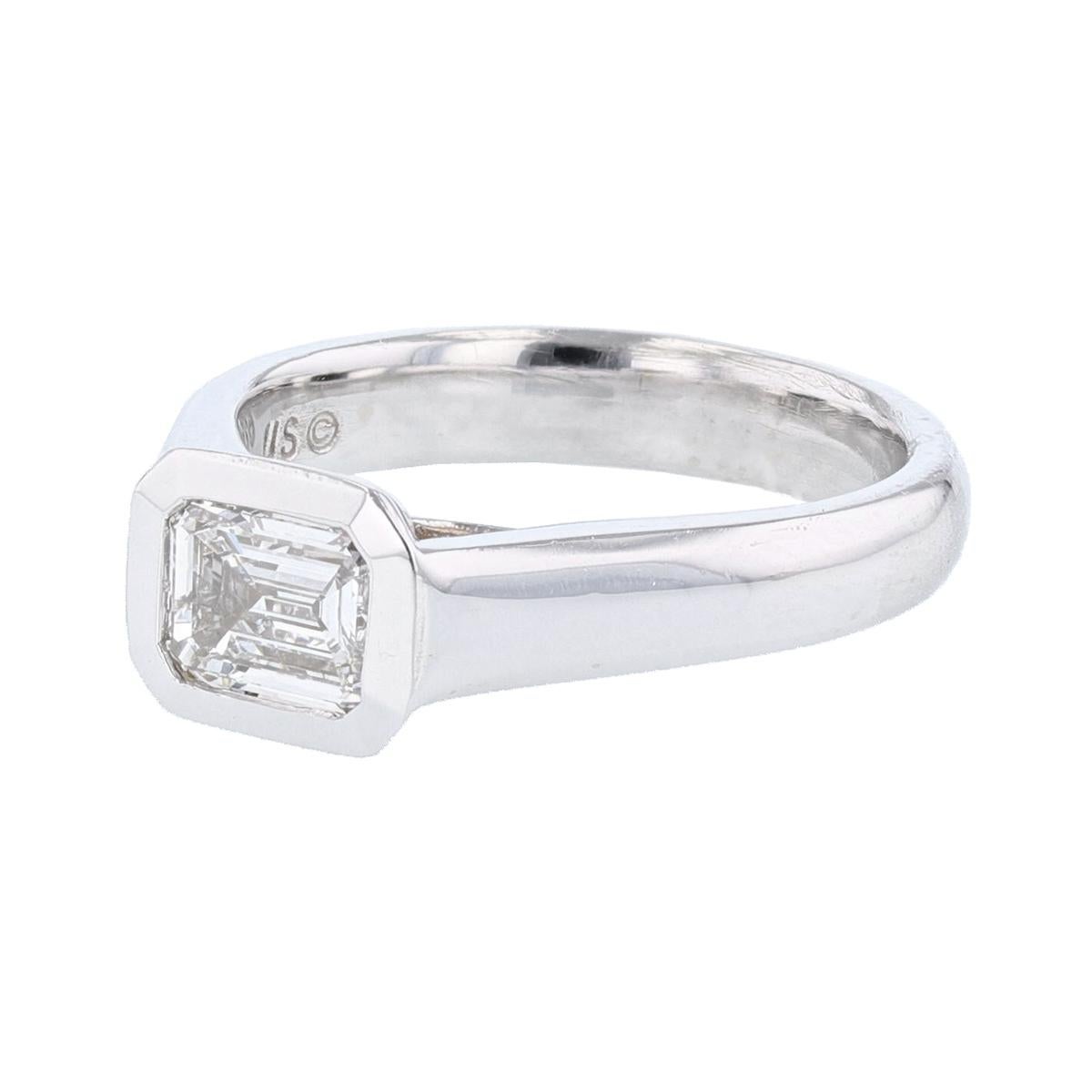 This ring is made with 14 karat white gold and features a bezel set  1.01ct  IGI certified emerald cut diamond (IGI certification number 9209818), with a color grade (E) and clarity grade (SI2). 