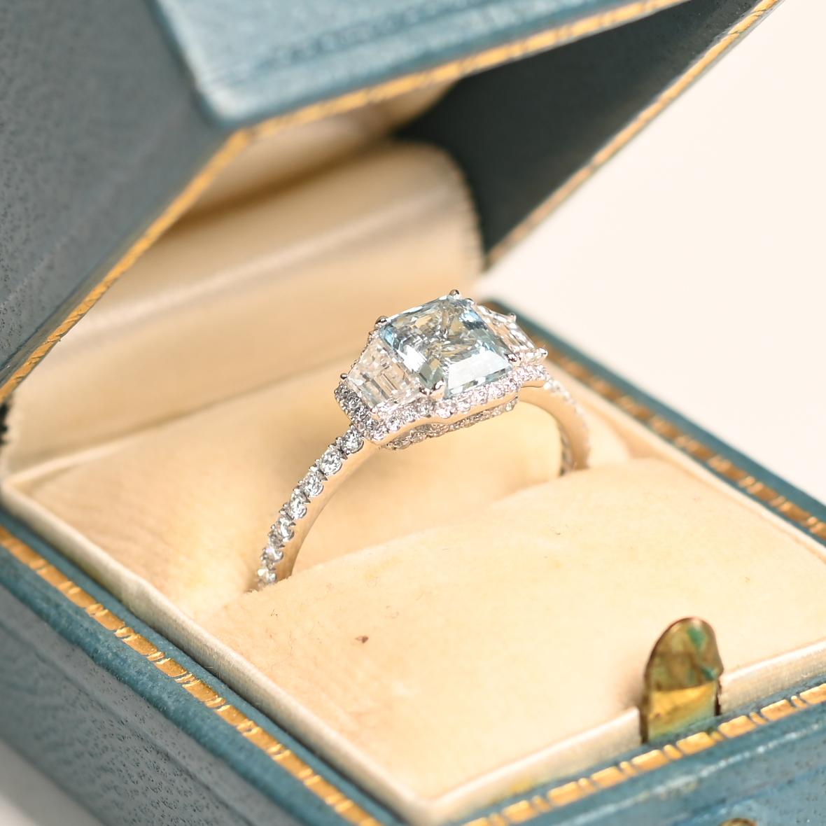 Questo anello con acquamarina e diamanti mette in mostra una splendida acquamarina di circa 0,70 carati con taglio a smeraldo, elegantemente fissata con delle griffe. La tonalità blu ghiaccio dell'acquamarina è splendidamente completata da due