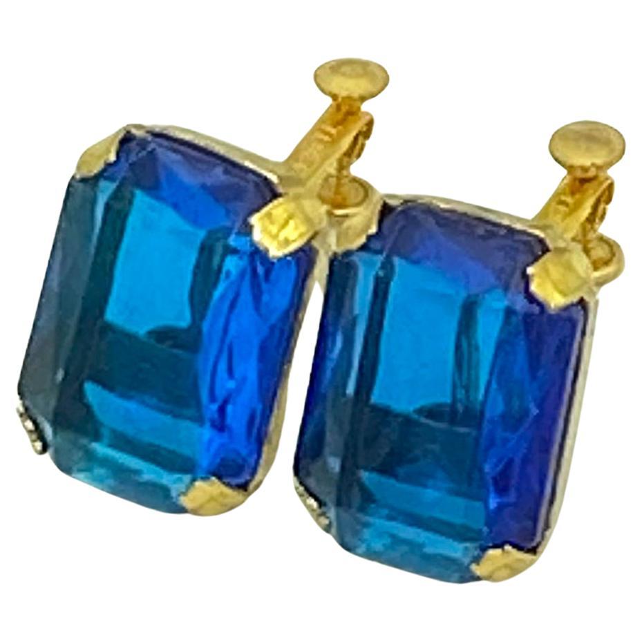 These are emerald-cut blue earrings with the Miriam Haskell mark. This pair of large London blue lucite stones are prong set in brass frames. They are marked Miriam Haskell on the clasp/screw. Perfect for that 