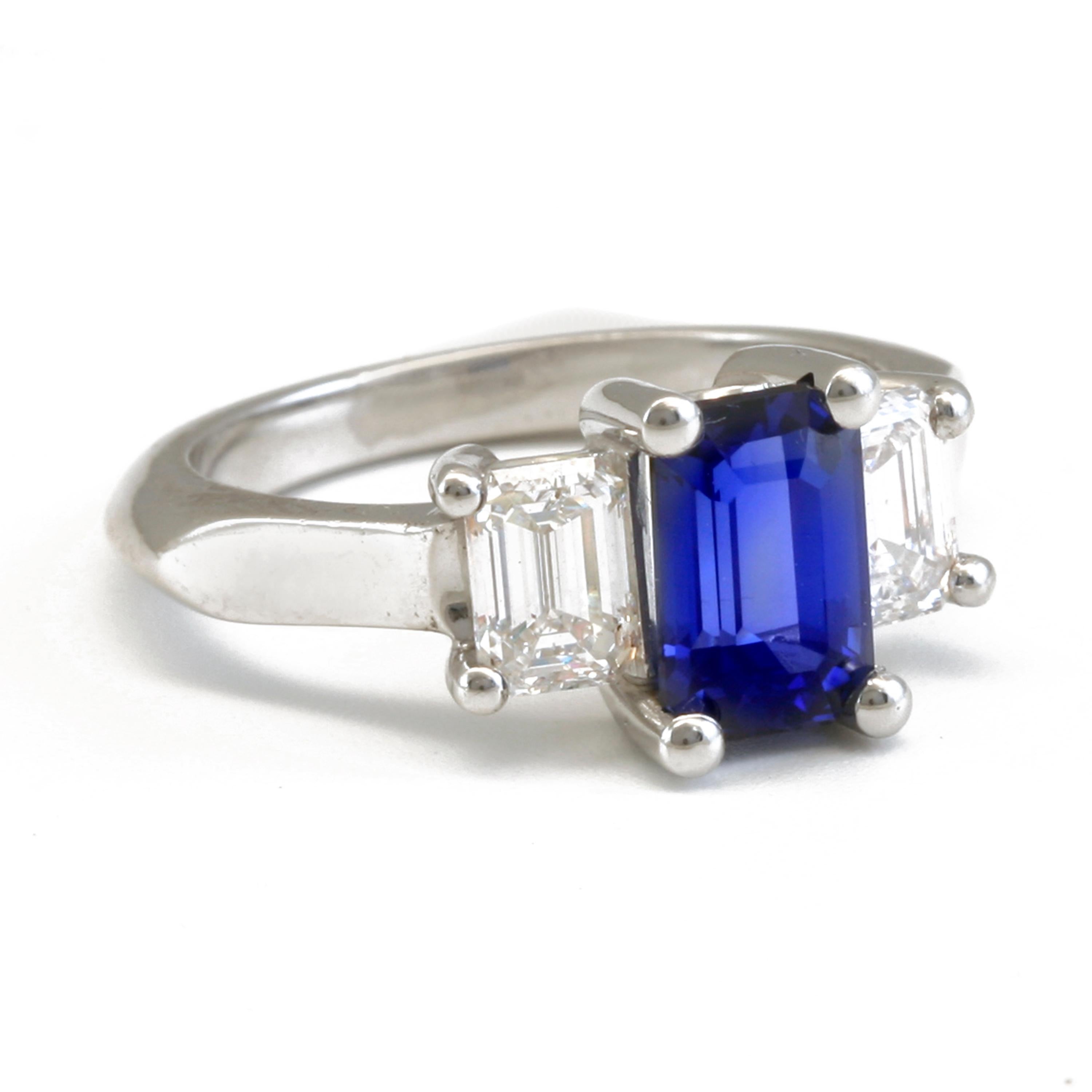 This emerald cut (emerald cut refers to the name of the gemstone's shape not gem type) Ceylon Blue is a 2.05 Carat Sapphire with 1.04 total carat weight in two side stones. The Diamonds have DE color, VS clarity, are also emerald cut, set in