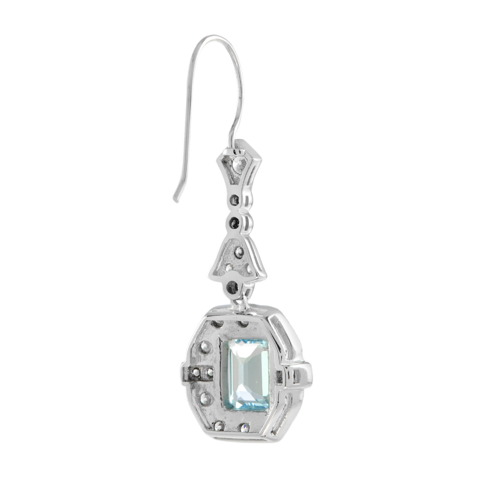 A gorgeous emerald cut sky blue topaz is presented in classic Art Deco style. The glorious gemstone radiates from within a sparkling halo of bright round cut diamonds punctuated east and west with a line of round diamonds, leading to a slightly