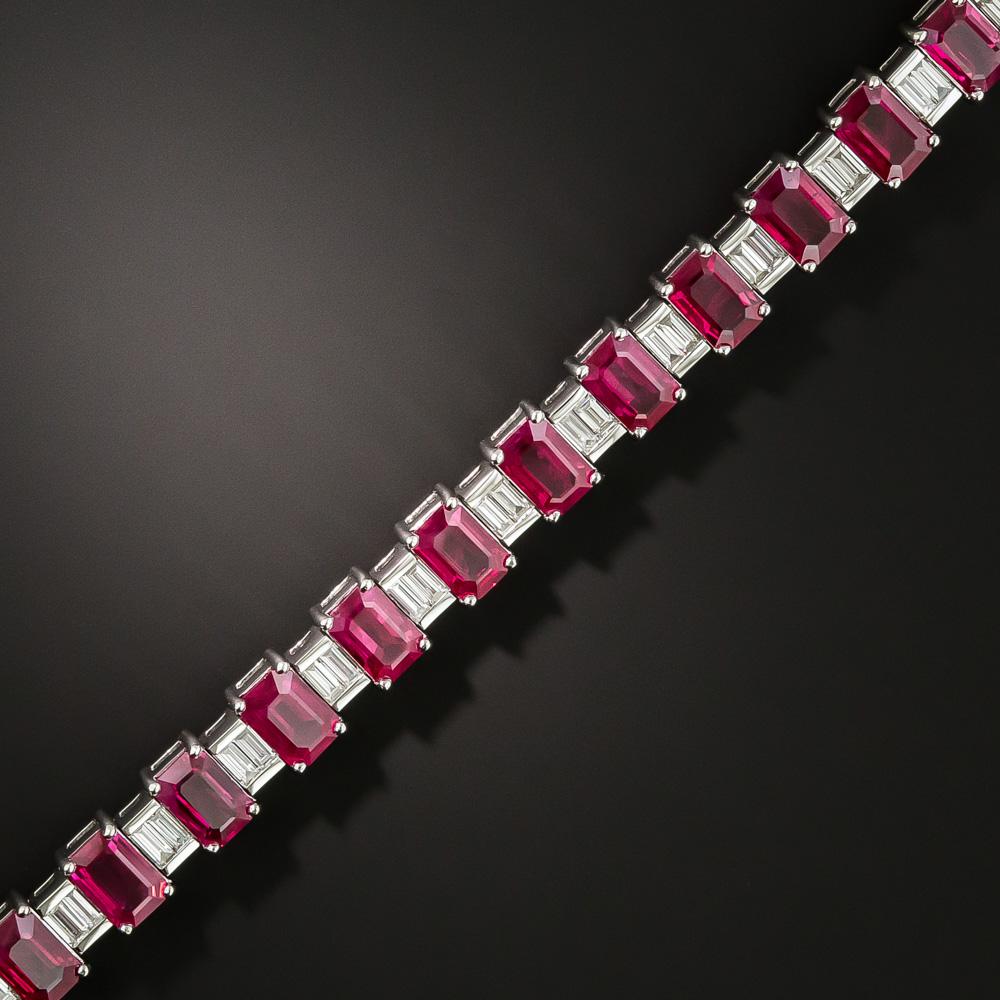 Twenty-four perfectly matched emerald-cut rubies, together weighing 14.00 carats and interspersed with seamlessly-set pairs of icy-white baguette diamonds, cast a gorgeous, glorious, electric candy apple red glow, all around this exceptional modern