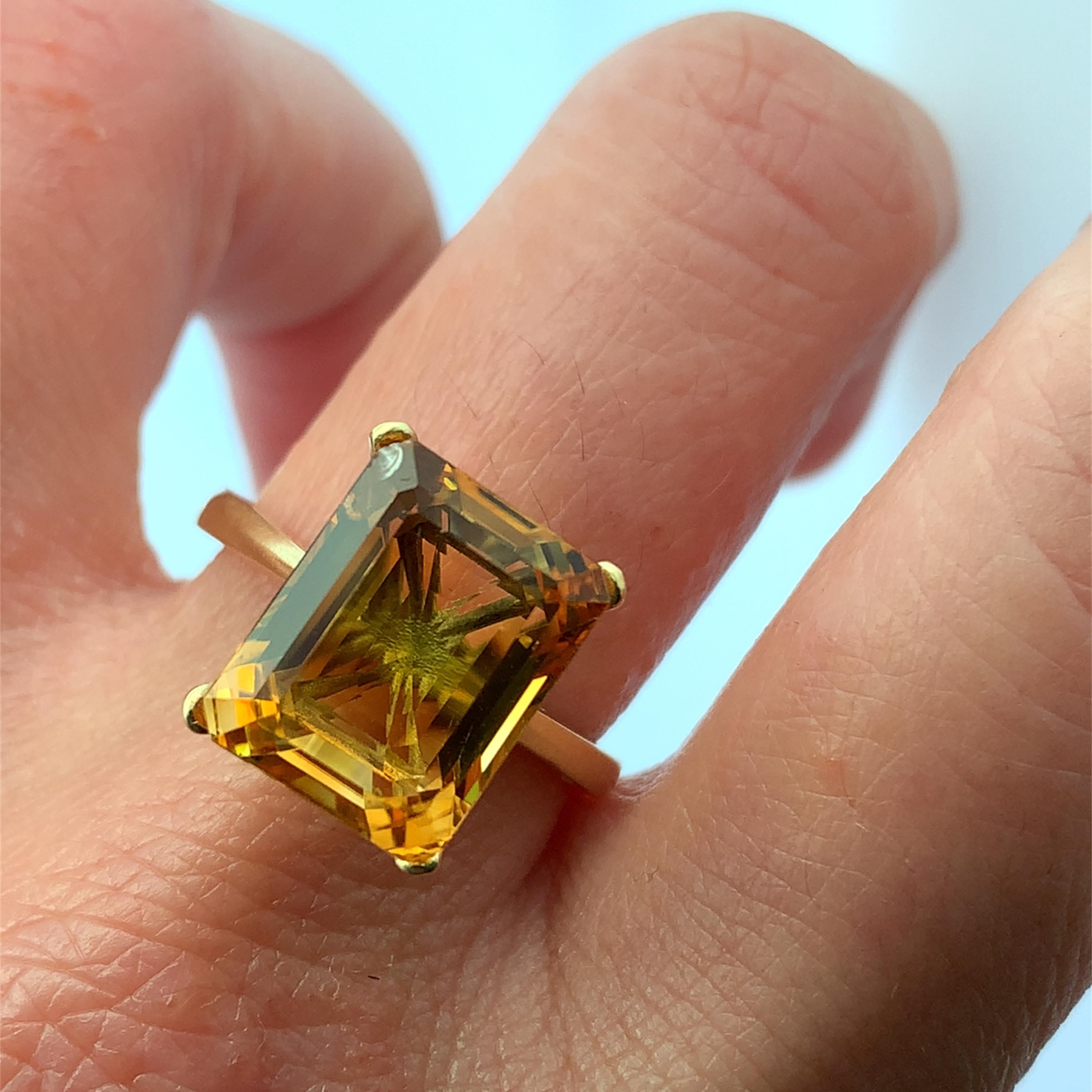 Questo splendido anello d'oro da cocktail o di fidanzamento in oro giallo 18k è caratterizzato da un'affascinante gemma citrina di colore arancione ambrato, taglio smeraldo da 7,50 carati, che misura circa 15x10 mm con SetH 8 mm e irradia calore ed
