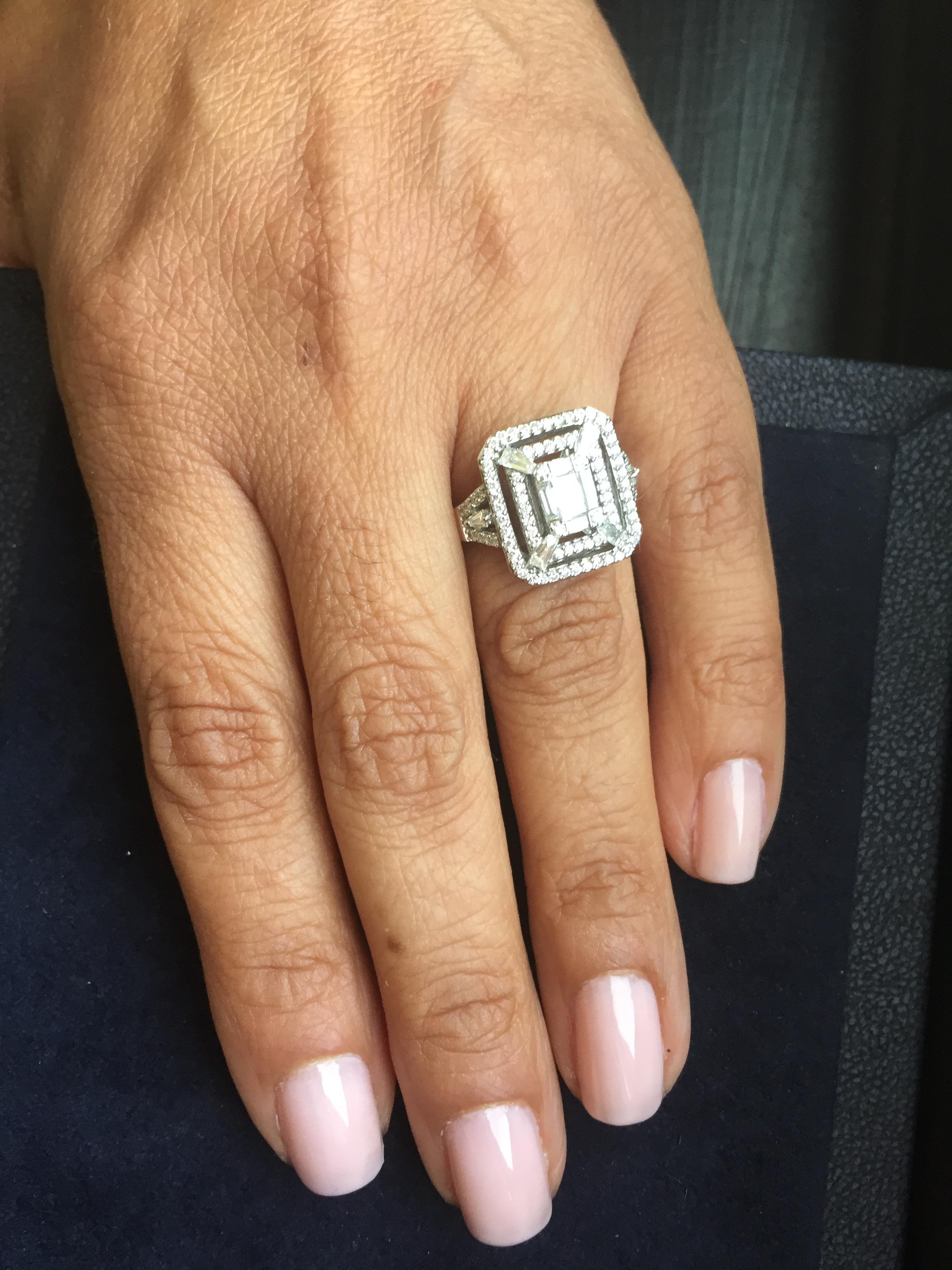 Dieser Cocktailring ist ein echtes Statement zu jedem Look. Dieser Ring hat einen Diamanten im Smaragdschliff in der Mitte und ist von zwei Reihen runder Diamanten umgeben. Dieser Ring ist in 18k Weißgold gefasst, Gesamtkaratgewicht ist 1,20, Farbe