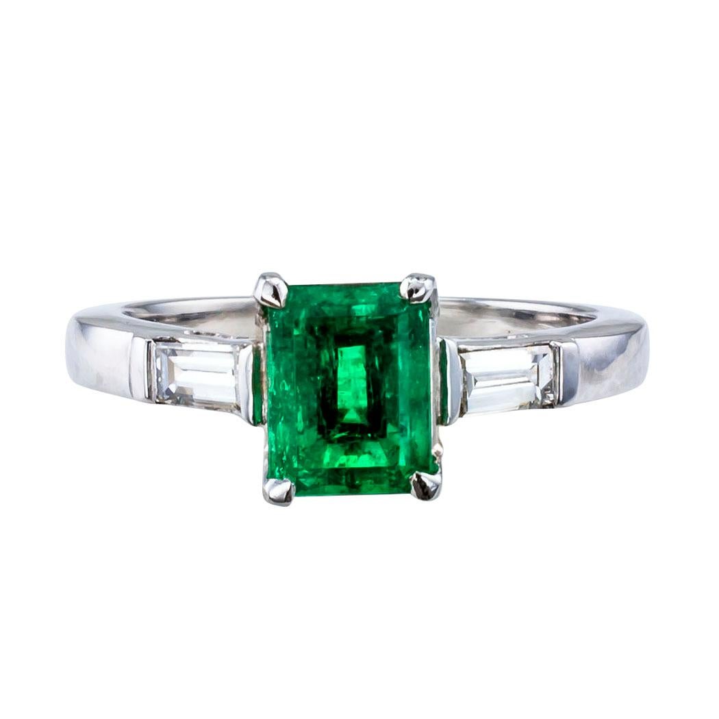 Estate 1970s emerald and diamond platinum ring. Centering upon an emerald-cut Colombian emerald weighing 1.12 carat, flanked by a pair of tapered baguette diamonds totaling approximately 0.28 carat, approximately H – I color and VS clarity, mounted