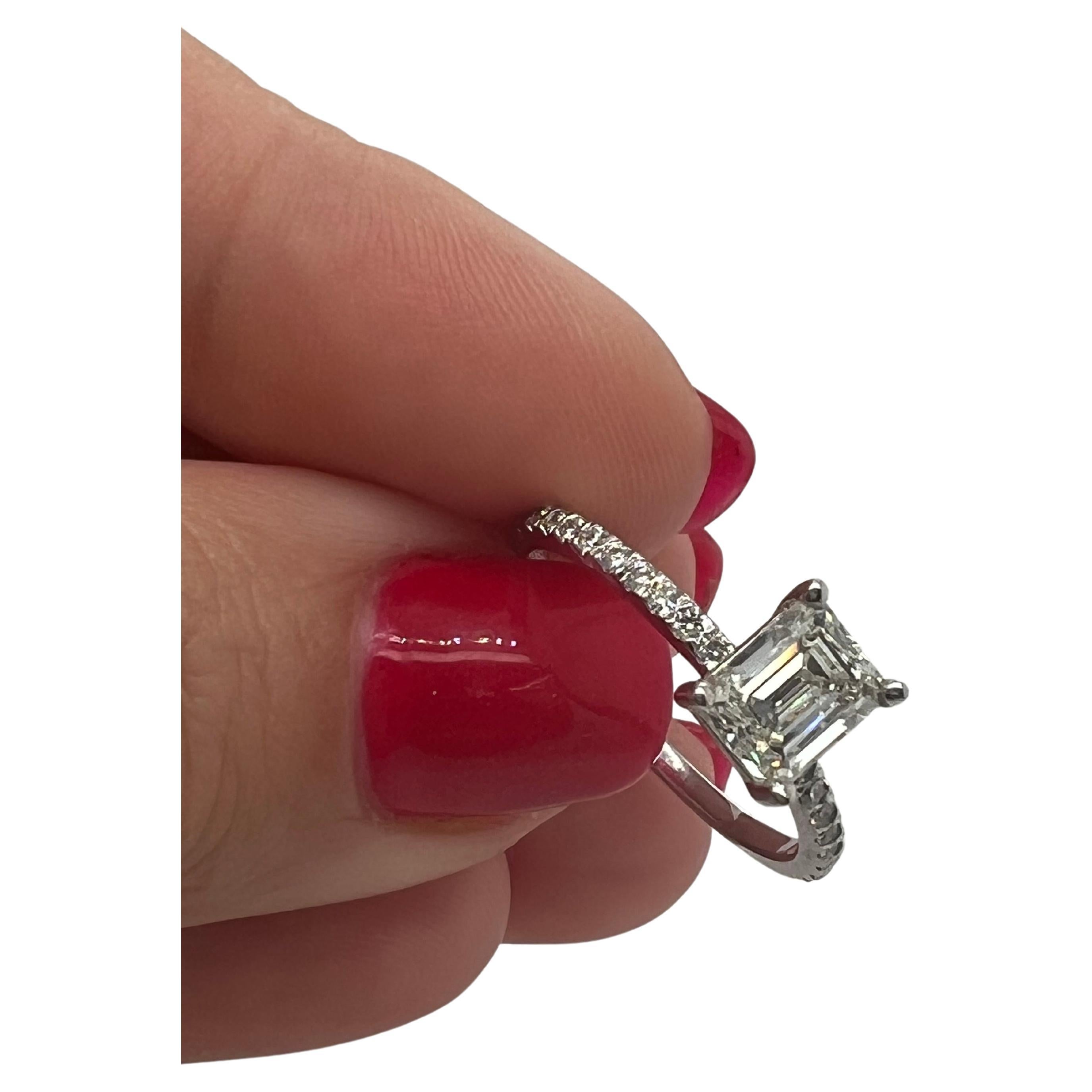 This exquisite engagement ring features a stunning 1.05-carat natural earth mined Emerald Cut diamond in J-K color and VS1 clarity, set in a 4-prong basket on a 1.80mm wide solid 18kt white gold shank with 0.24 carats total weight of natural earth