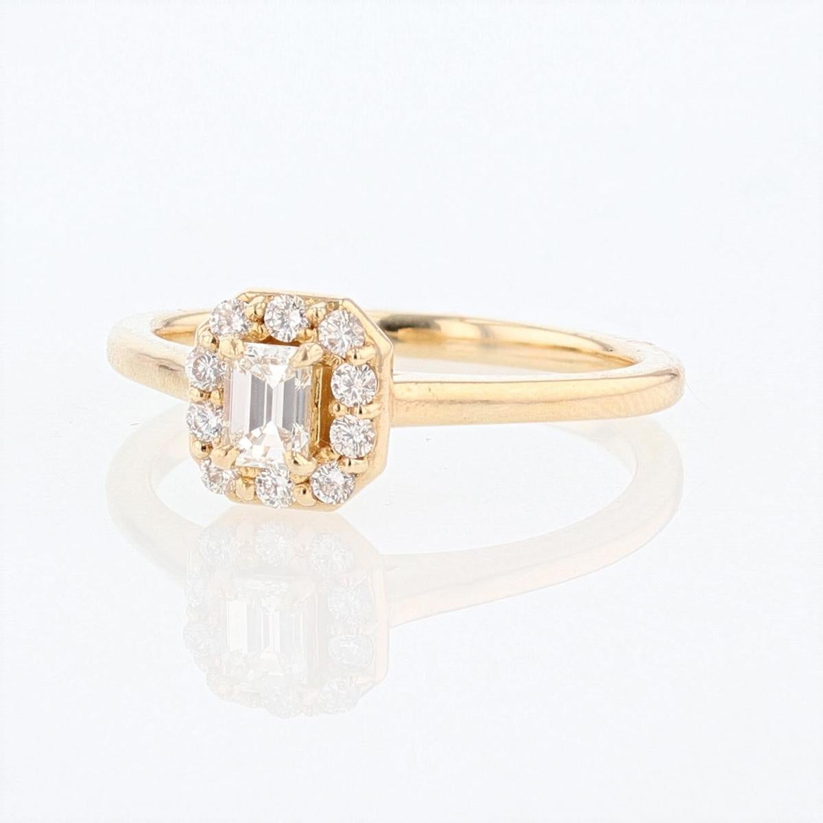 This diamond engagement ring is made with 14 karat yellow gold and features 1 prong set emerald cut diamond weighing 0.28cts and 10 prong set round diamonds weighing 0.19cts with a color grade (I) and clarity grade (SI2). 