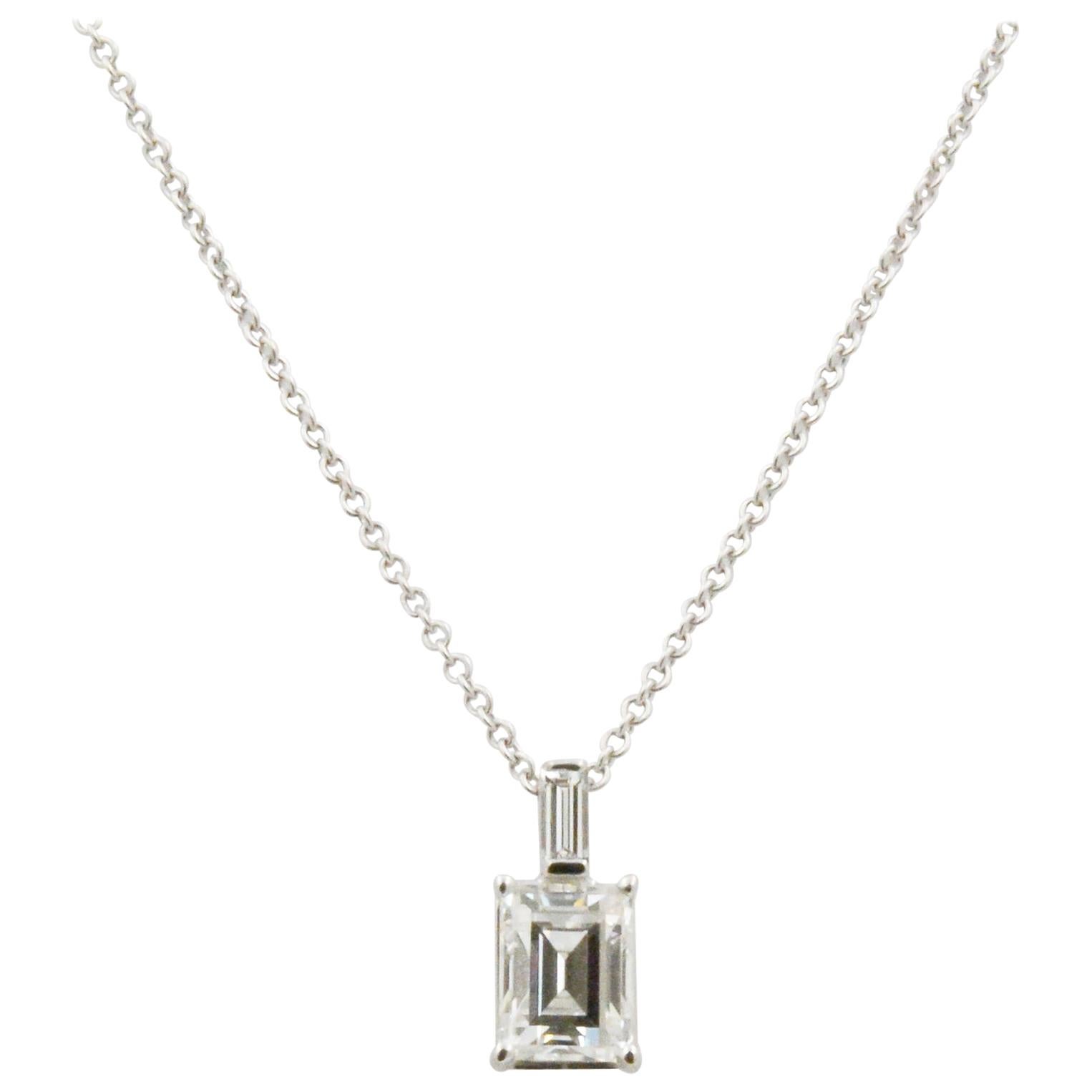 This charming 18k white gold pendant features one emerald cut diamond, with J coloring and VS2 clarity and 1.33ctw and one baguette diamond on bail, weighing .11ctw. 