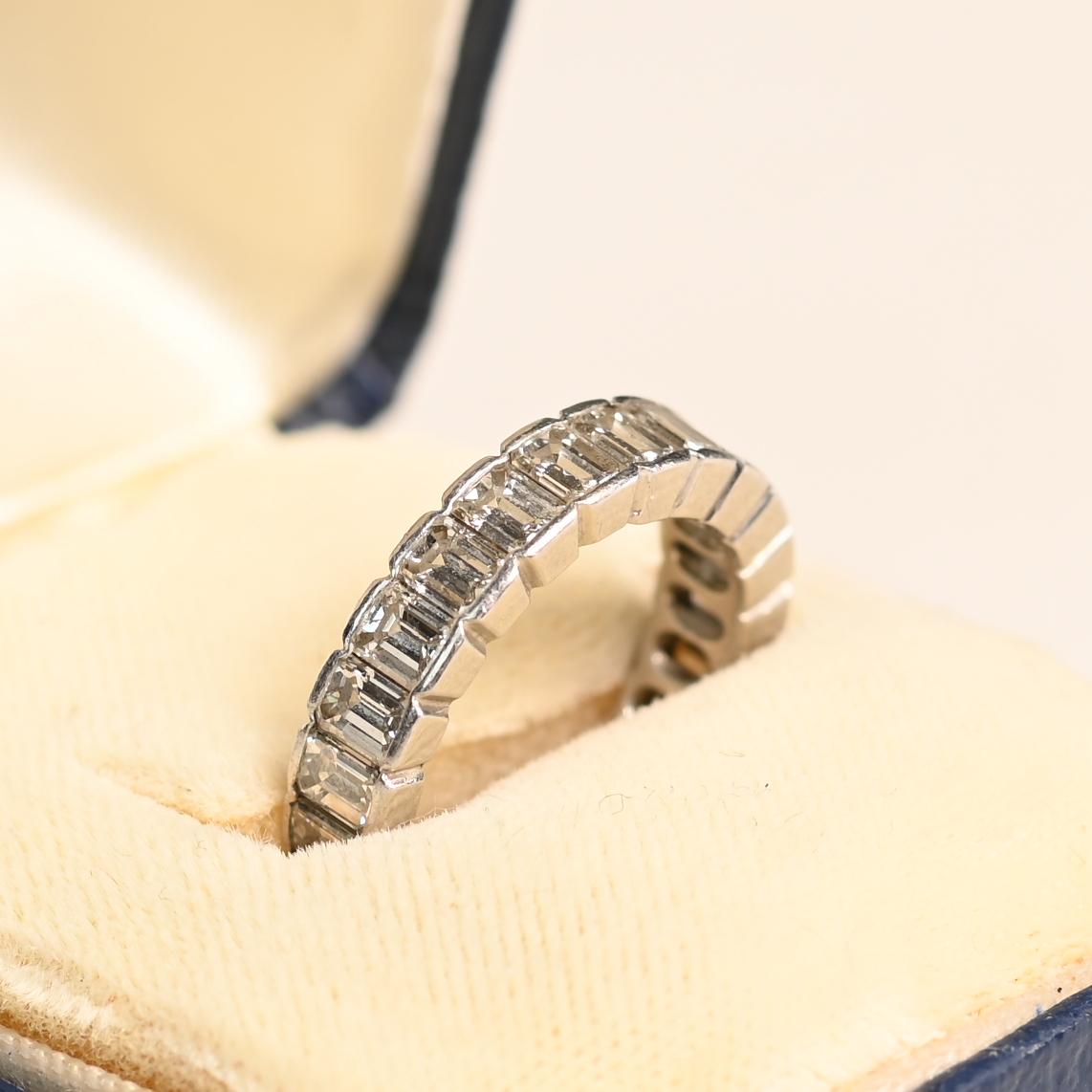 Esta exquisita banda de diamantes talla esmeralda es una verdadera declaración de elegancia y artesanía. Con aproximadamente 3,8 quilates de diamantes talla esmeralda, cada piedra está meticulosamente engastada en semibiseles para realzar su brillo