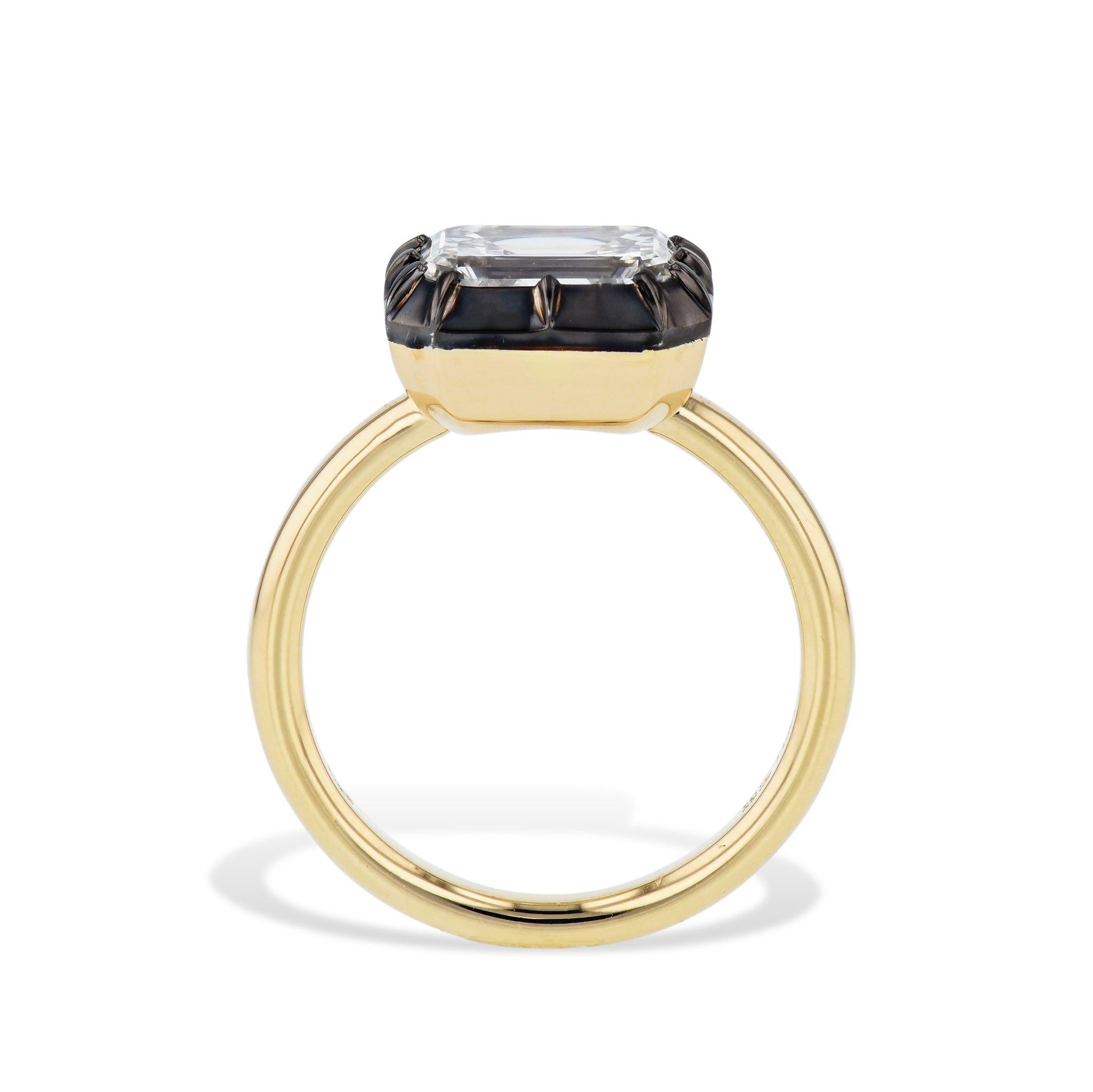 This exquisite ring features a stunning emerald cut diamond set in a black ruthenium bezel, with platinum prongs and 18kt yellow gold shank. Its east-west mounted diamond adds a touch of uniqueness to its handmade design. Available in a size 6, it's