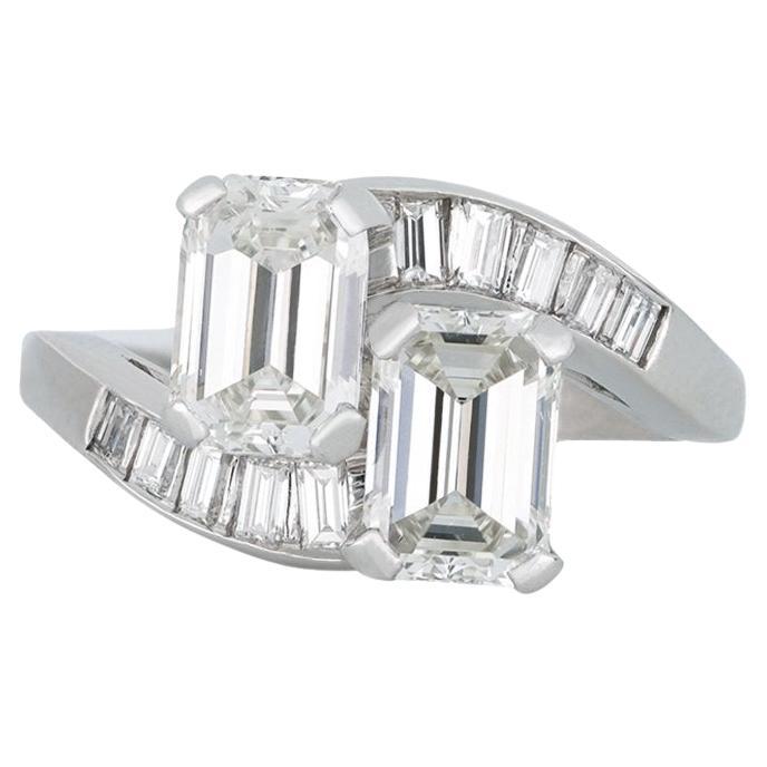 Emerald-cut diamond cross over ring, American, circa 1950. For Sale