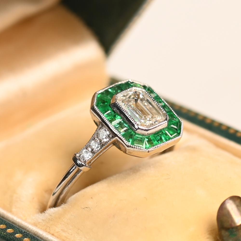 Ein fesselnder Halo Emerald Cut Diamant, dieses exquisite Stück zentriert sich um einen GIA-zertifizierten Emerald Cut Diamanten mit einem Gewicht von ca. 0,8 Karat, eingestuft H für Farbe und VS2 für Klarheit. Die klaren, geometrischen Facetten des
