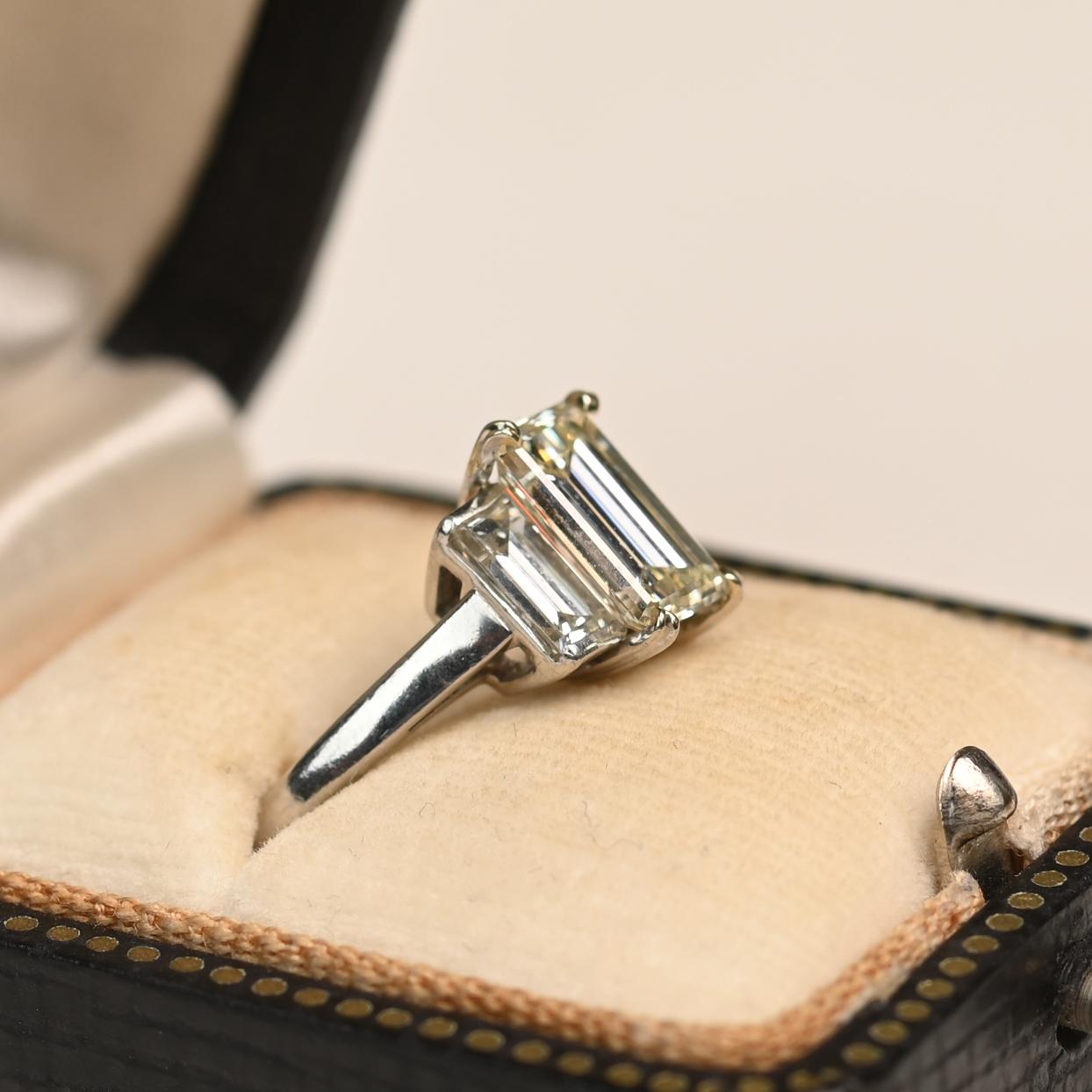 This elegant platinum ring showcases a captivating emerald-cut diamond weighing approximately 1.50 carats. The center stone, with an N color and VS1–SI2 clarity, is securely held in a refined prong setting that beautifully highlights its step-cut
