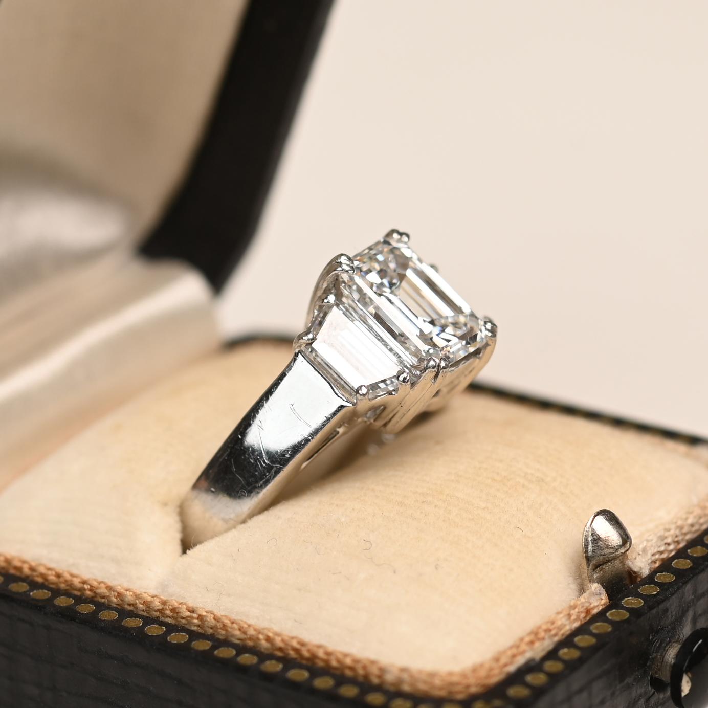 This exquisite platinum ring showcases a GIA-certified emerald-cut diamond weighing approximately 2.00 carats. The center stone boasts an exceptional E color and VS2 clarity, securely set in a refined prong setting that highlights its striking