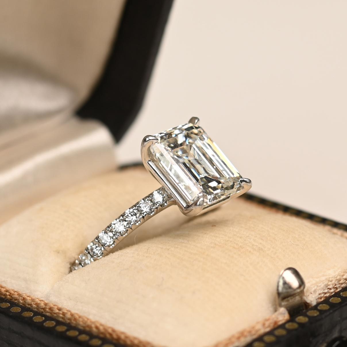 This elegant platinum ring features a GIA-certified emerald-cut diamond weighing approximately 2.70 carats. The center stone, graded H color and SI2 clarity, is secured in a classic prong setting that highlights its clean lines and radiant