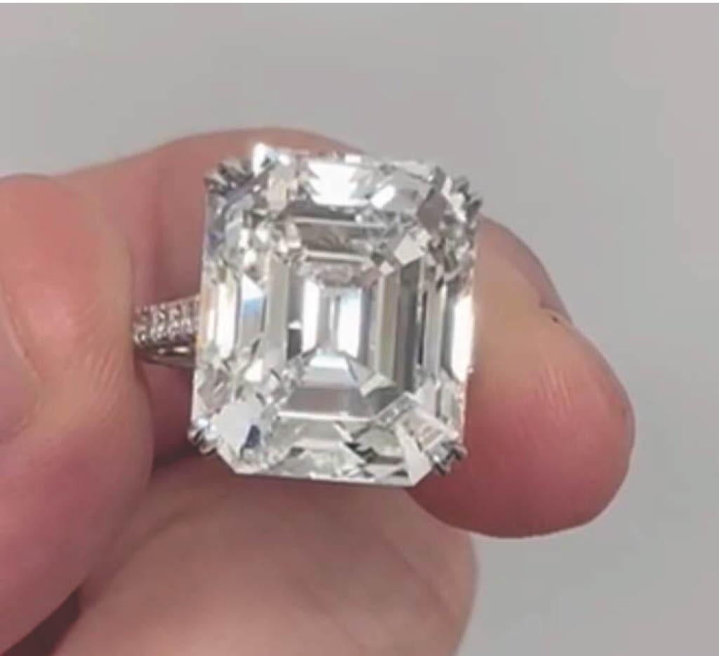 A breathtaking 20+ carat diamond takes center stage in this extraordinary platinum ring, showcasing the refined geometry of the emerald cut. GIA-certified, the central diamond weighs 20.81 carats, with a crisp H color and VS2 clarity, complemented