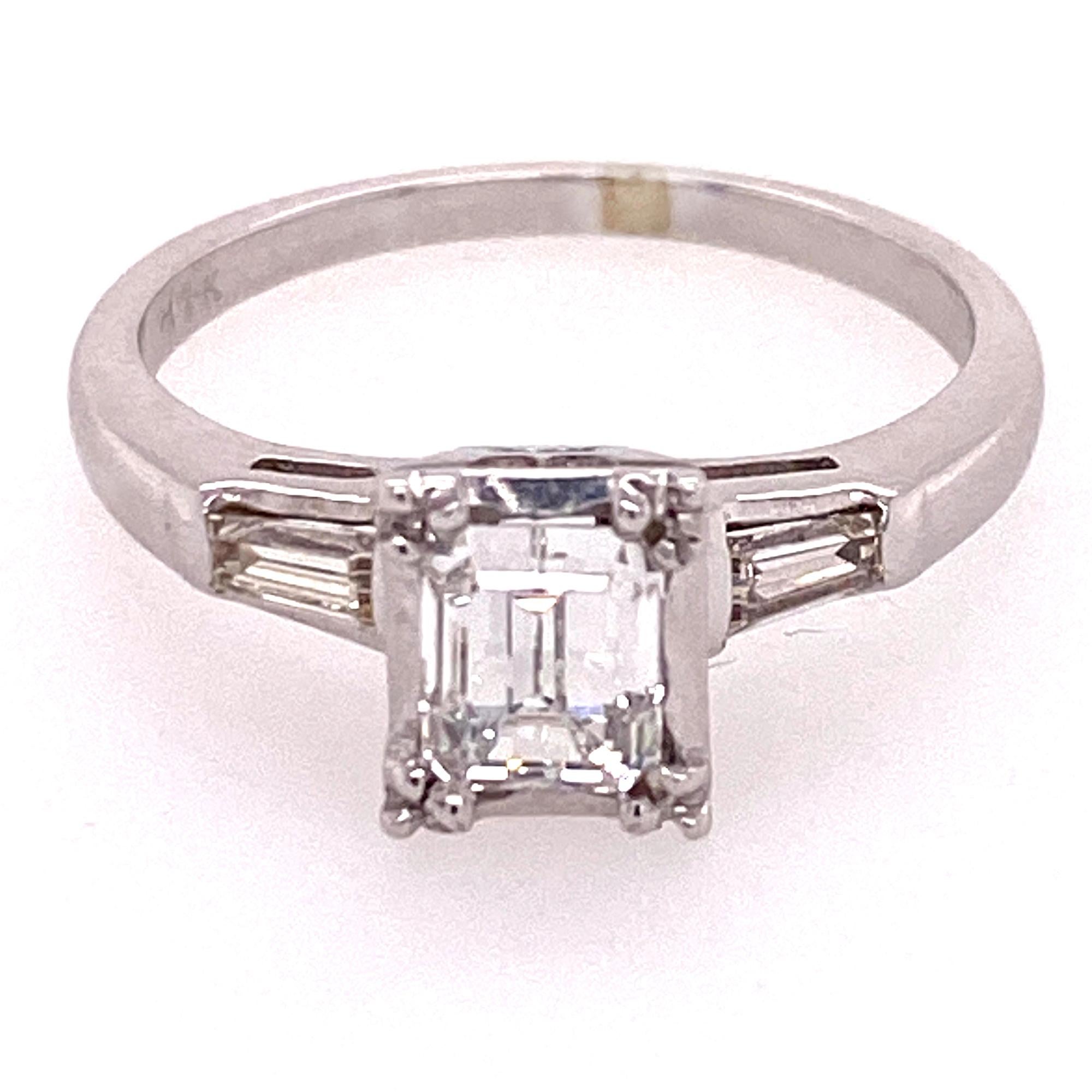 Beautiful emerald cut diamond engagement ring fashioned in 14 karat white gold. The emerald cut diamond weighs .77 carats and is graded by the GIA G color and VVS2 clarity. The emerald cut is flanked by two tapered baguettes weighing .04 ctw. The