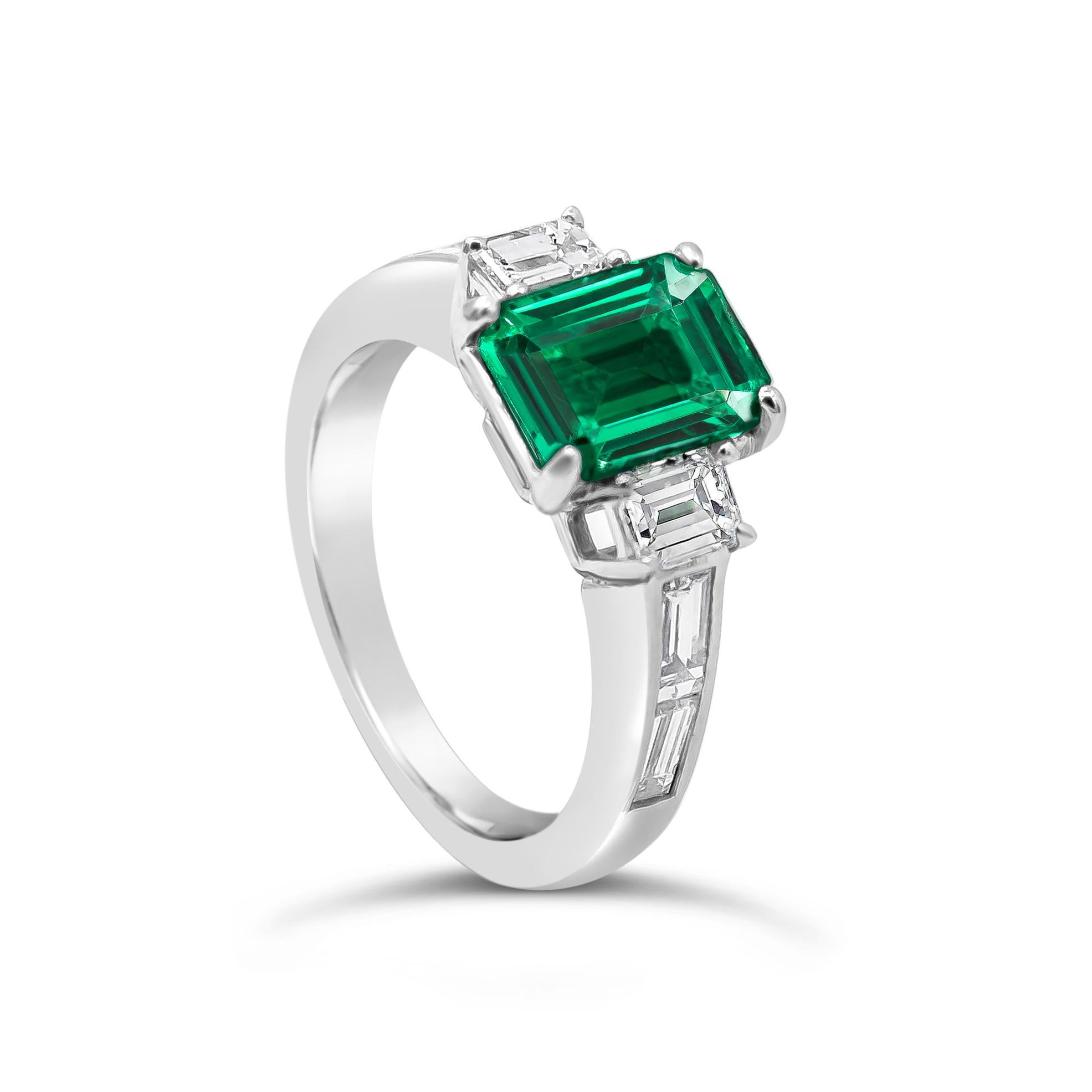A wonderful engagement ring, showcasing a 1.66 carats emerald cut green emerald, set on a four prong setting. Flanked by two perfectly matching emerald cut diamonds and accented by channel-set diamonds on a half-way setting. Accent diamonds weigh
