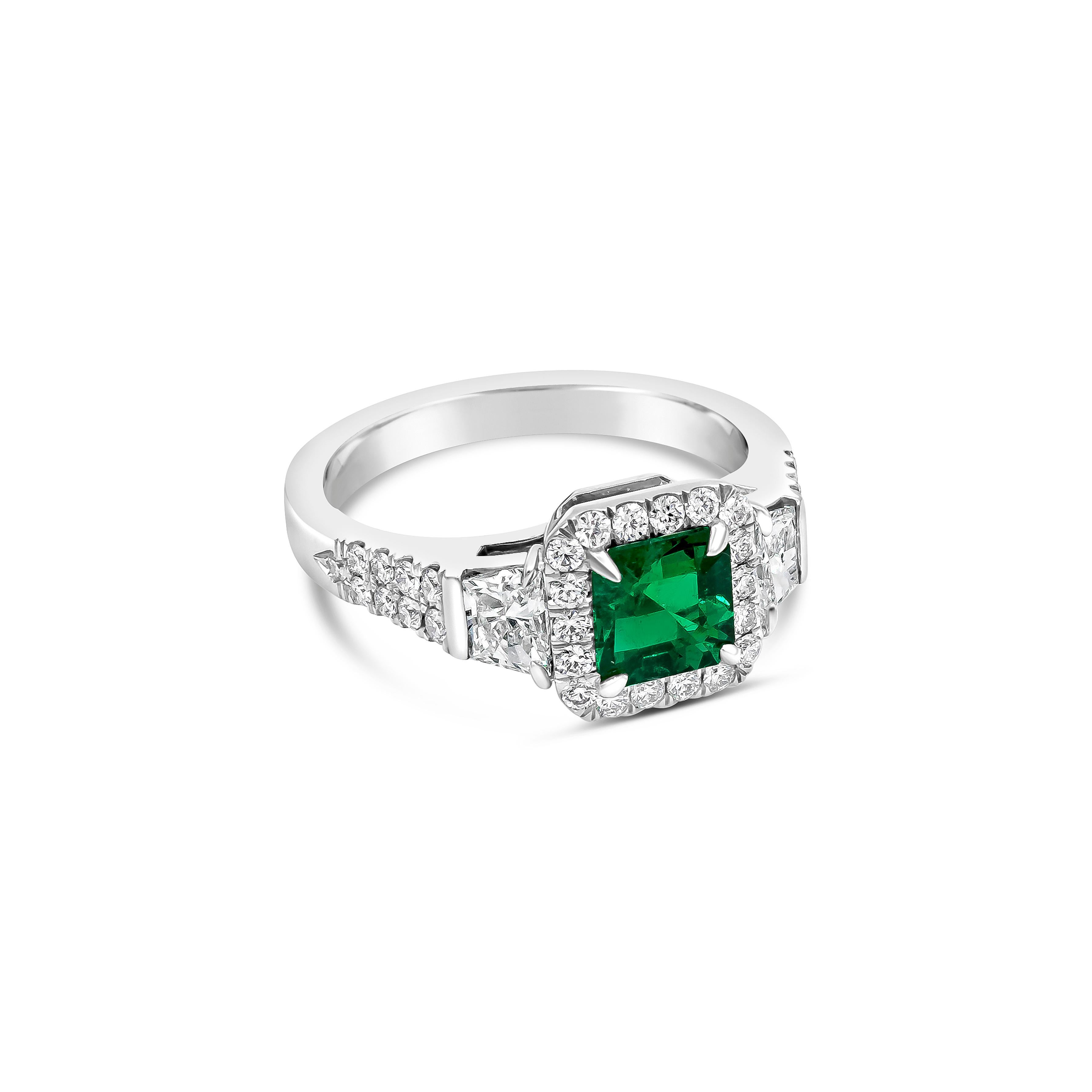 Showcases a square-shaped green emerald weighing 0.80 carats, surrounded by a single row of round diamonds. Center emerald flanked by brilliant trapezoid diamonds on an accented platinum band. Diamonds weigh 1.18 carats total. 

