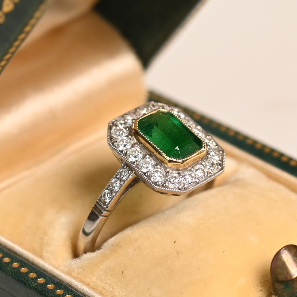 Questo squisito anello di fidanzamento mette in mostra un sorprendente smeraldo taglio smeraldo, incastonato in un ricco oro giallo 18 carati e circondato da un'aureola di abbaglianti diamanti taglio vecchio europeo. Lo smeraldo centrale, del peso