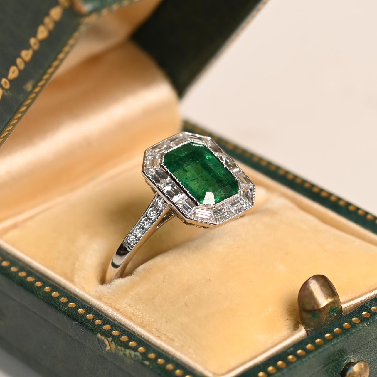 Este exquisito anillo de compromiso con halo exhibe una impresionante esmeralda natural de aprox. 1,50 quilates, tallada en una sofisticada forma de esmeralda. La vibrante gema verde está engastada con seguridad en un bisel de platino, resaltando su