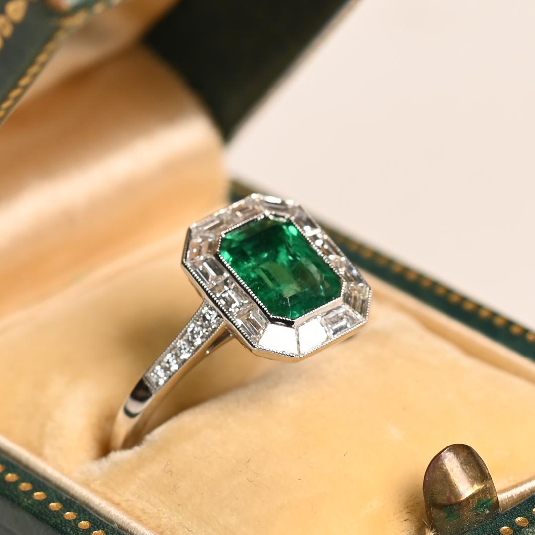Questo squisito anello di fidanzamento con aureola mette in mostra un vivido smeraldo naturale di circa 1,20 carati, sapientemente tagliato nella classica forma a smeraldo e incastonato saldamente al centro. La ricca tonalità verde dello smeraldo è