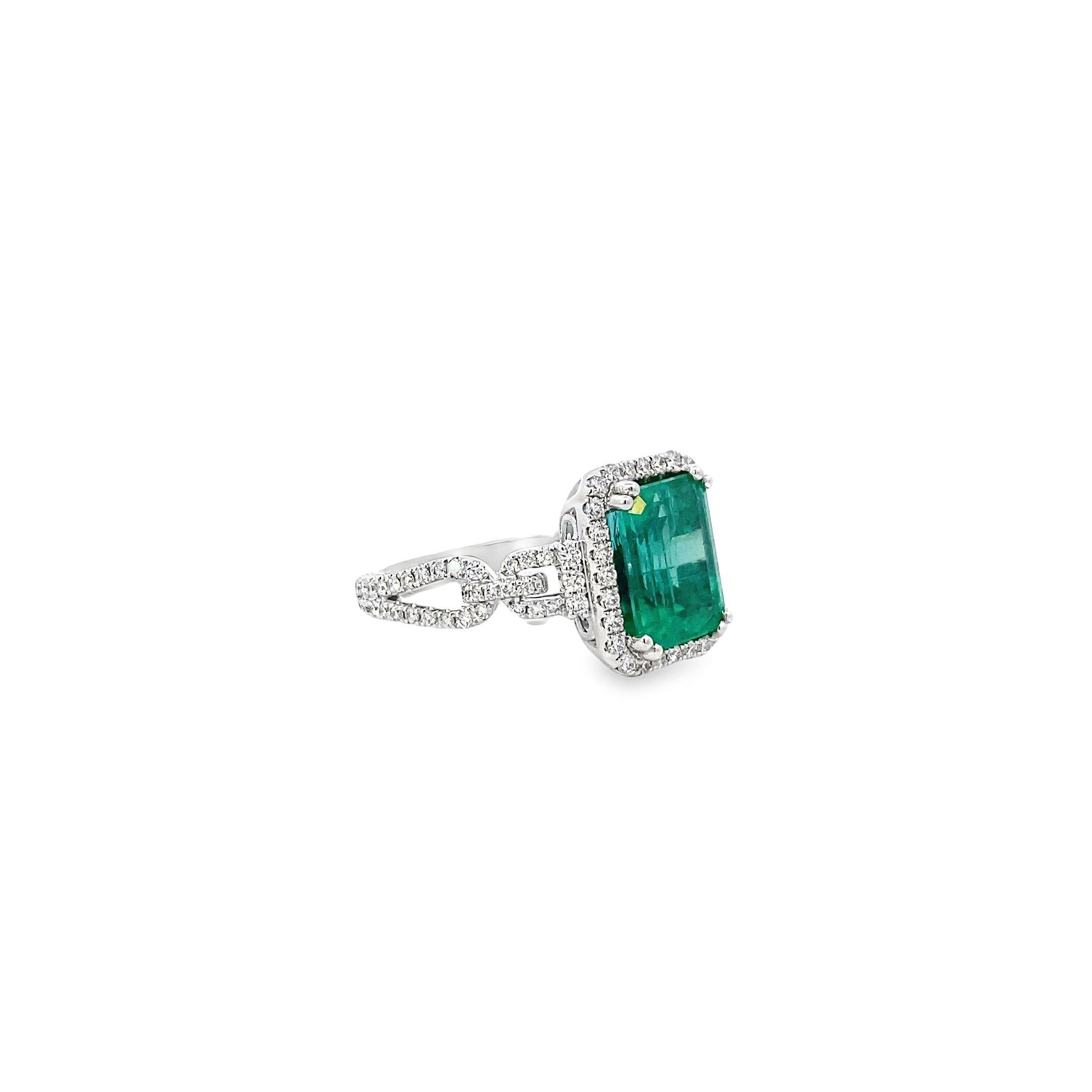 This stunning ring exudes a timeless elegance with its classic design and modern twist. Crafted in 18k white gold, the prong-set emerald-cut emerald at the center commands attention with its vibrant green hue of 3.66 carats. Surrounding the emerald