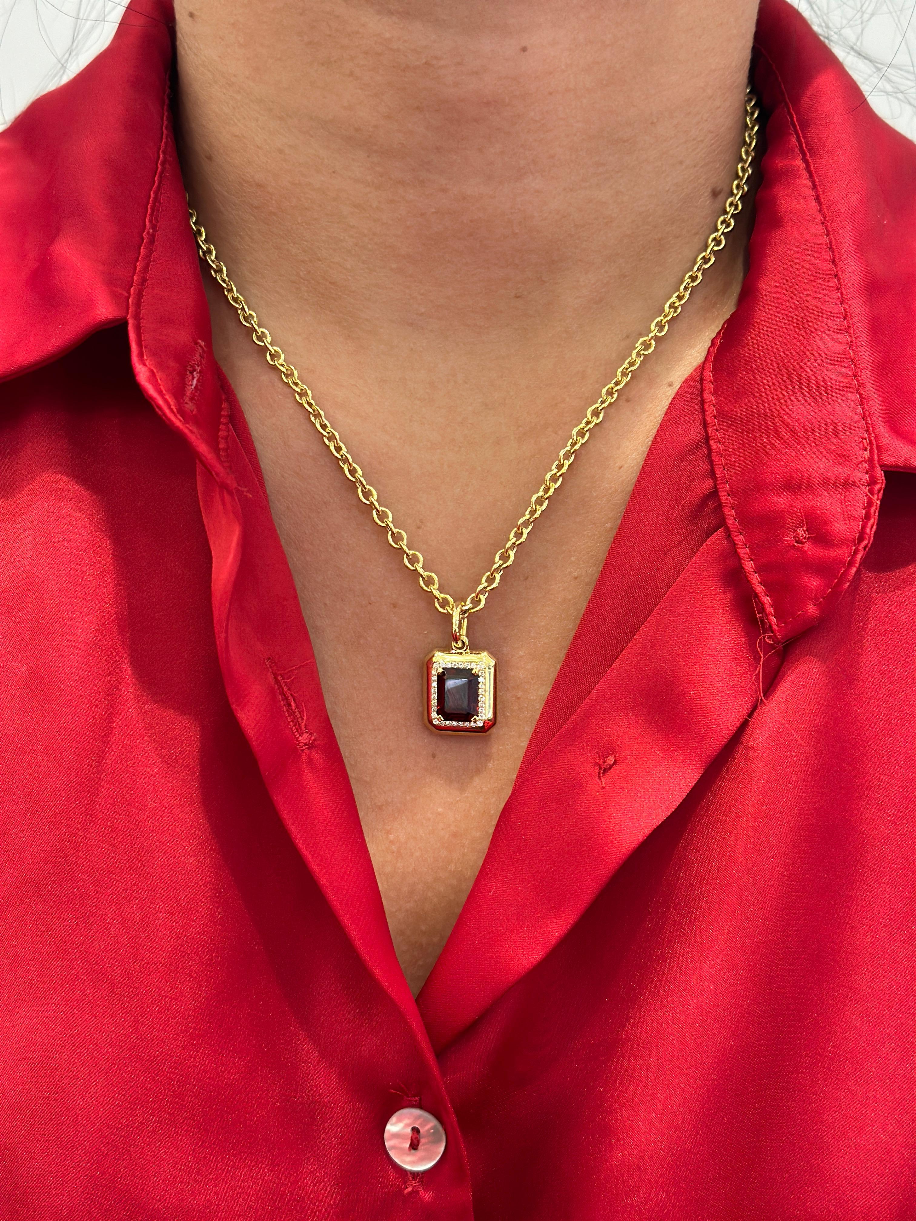 Faites preuve d'audace avec ce pendentif en grenat taillé en émeraude, élégamment serti en or jaune 18 carats et rehaussé de diamants étincelants. Le grenat rouge foncé de 9x7 mm est d'une beauté intemporelle, rehaussé par 0,13 ct de diamants