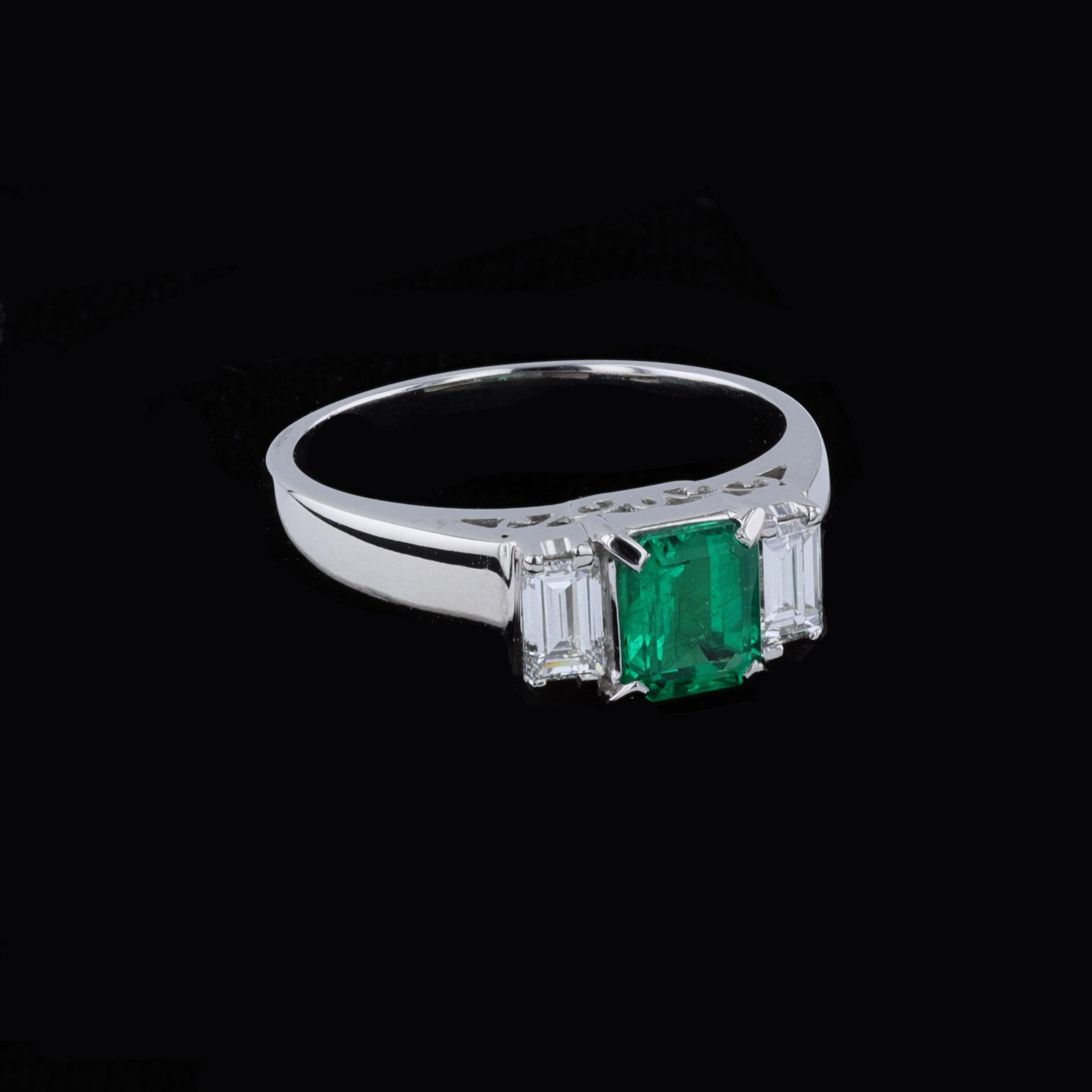 0.68ct Emerald 0.40ct Diamond Platinum Ring. The ring is centered with emerald cut emerald that weighs approximately 0.68ct. The center stone is accentuated by 2 emerald cut diamonds that weigh approximately 0.40ct. The color of the diamonds is G