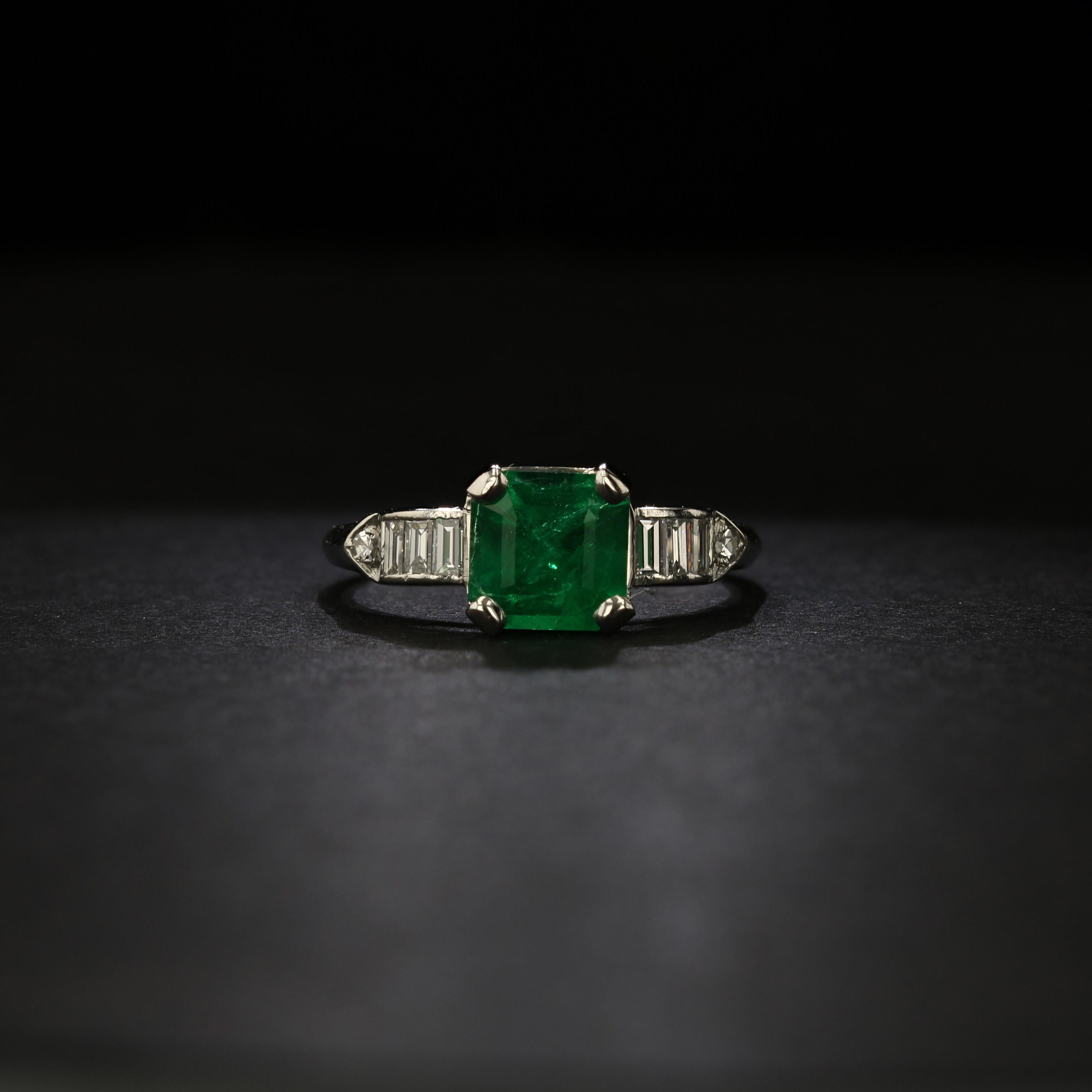 An emerald-cut green emerald is the feature of this estate ring crafted in polished platinum. A half dozen baguette diamonds and a pair of round diamonds grace the shoulders of the ring for added shine.

The emerald weighs approximately 1.17 carat