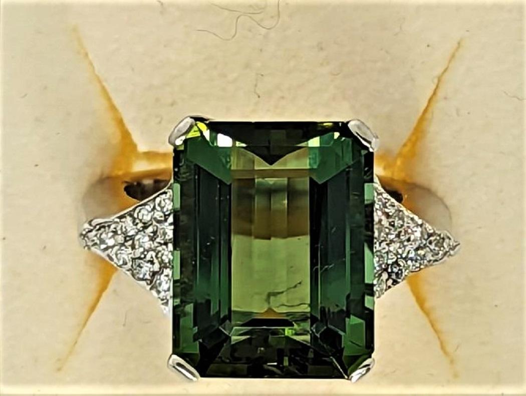 Green Emerald Cut Tourmaline measuring 14.76x11.52 mm and weighing 11.04 cts is set in an 18K White Gold mounting weighing 10.3 grams.  Each of the shoulders of the ring contain 20 diamonds that weigh 0.09 cts Total Weight of the diamonds 0.18 cts. 