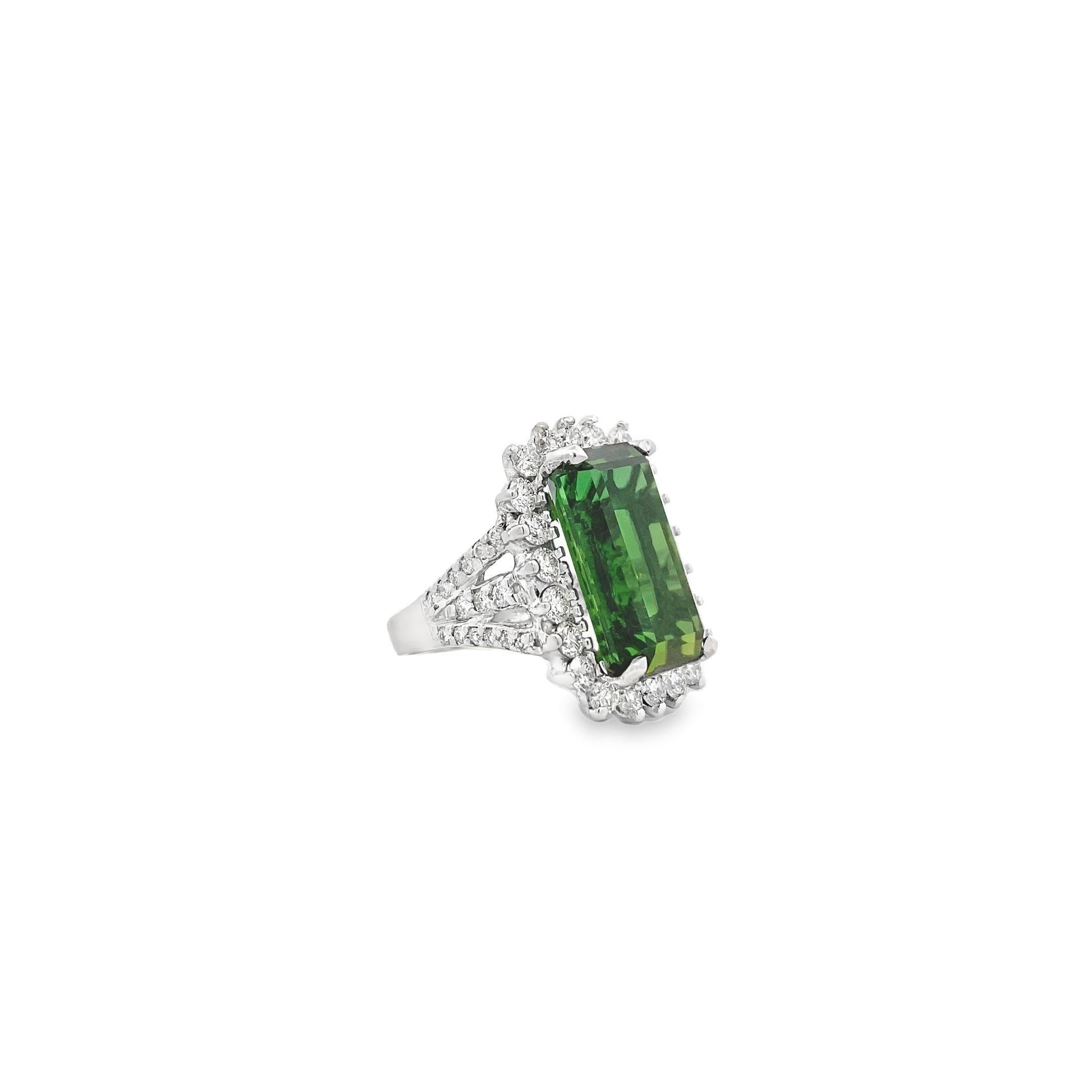 This exquisite ring, set in 14k white gold, features a 14.78 carat emerald-cut green tourmaline as its centerpiece. The vibrant tourmaline is surrounded by a halo of 2.23 carats of prong-set round diamonds, enhancing the depth and brilliance of the
