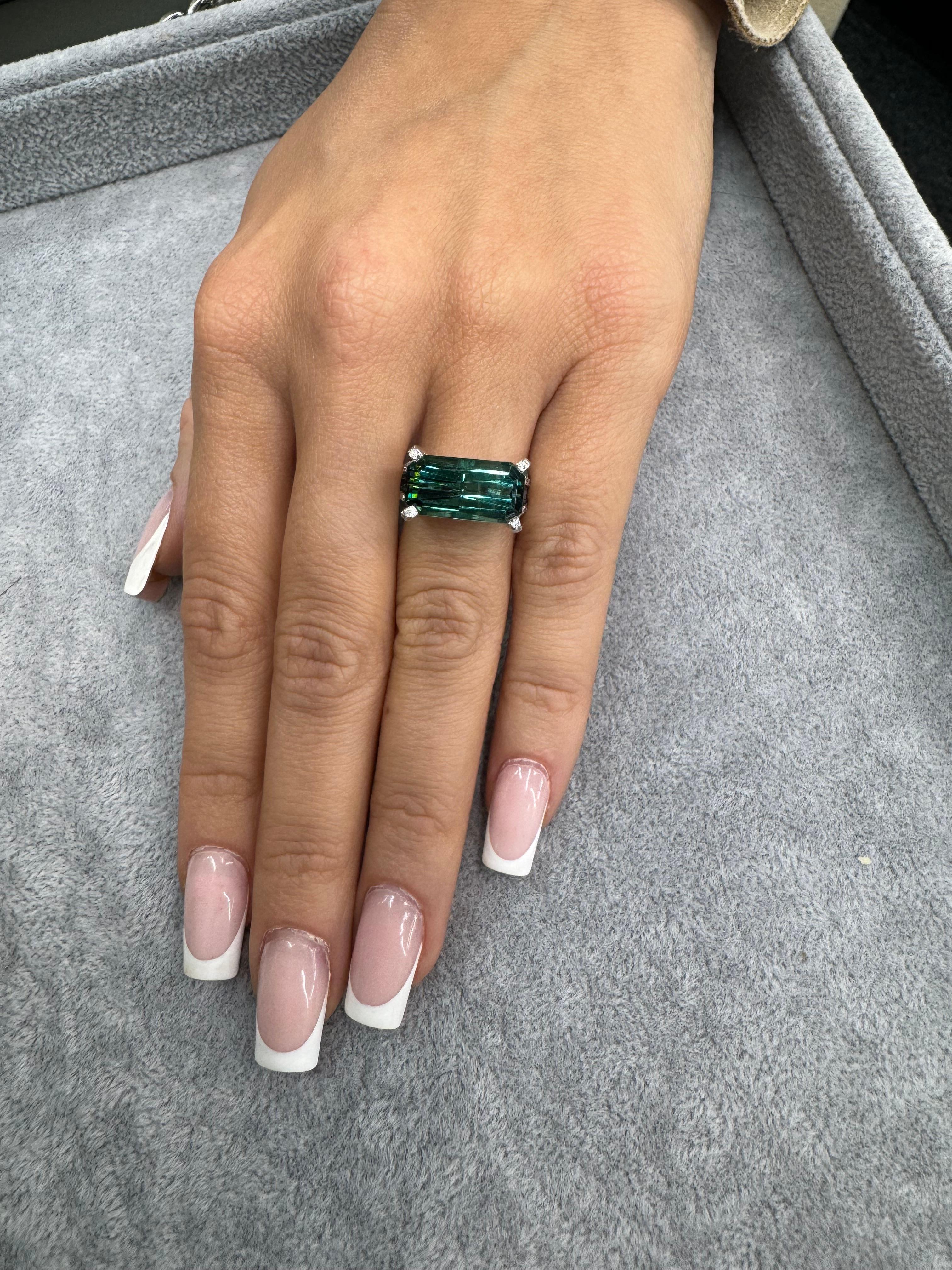 Emerald cut Indicolite Tourmaline weighing 6.11 carats with a diamond split shank mounting weighing 0.80 carats, in 18 karat white gold. 

Indicolite Tourmaline
14.8 mm x 7.7 mm
