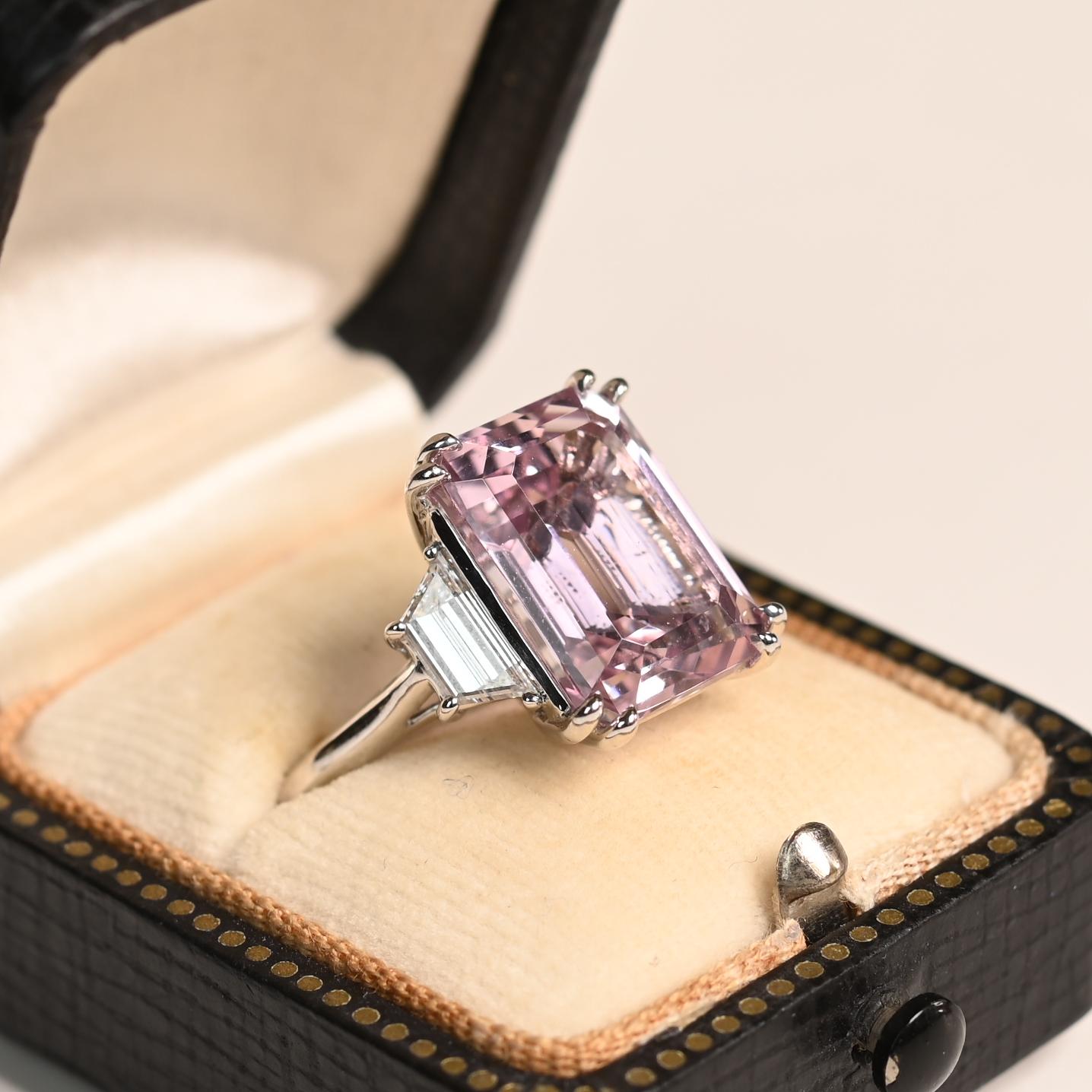 Este exquisito anillo de platino exhibe una impresionante kunzita natural de aprox. 9,00 quilates, expertamente engastada para resaltar su extraordinaria claridad y su vivo tono rosa. La piedra central de talla esmeralda exhibe un brillo