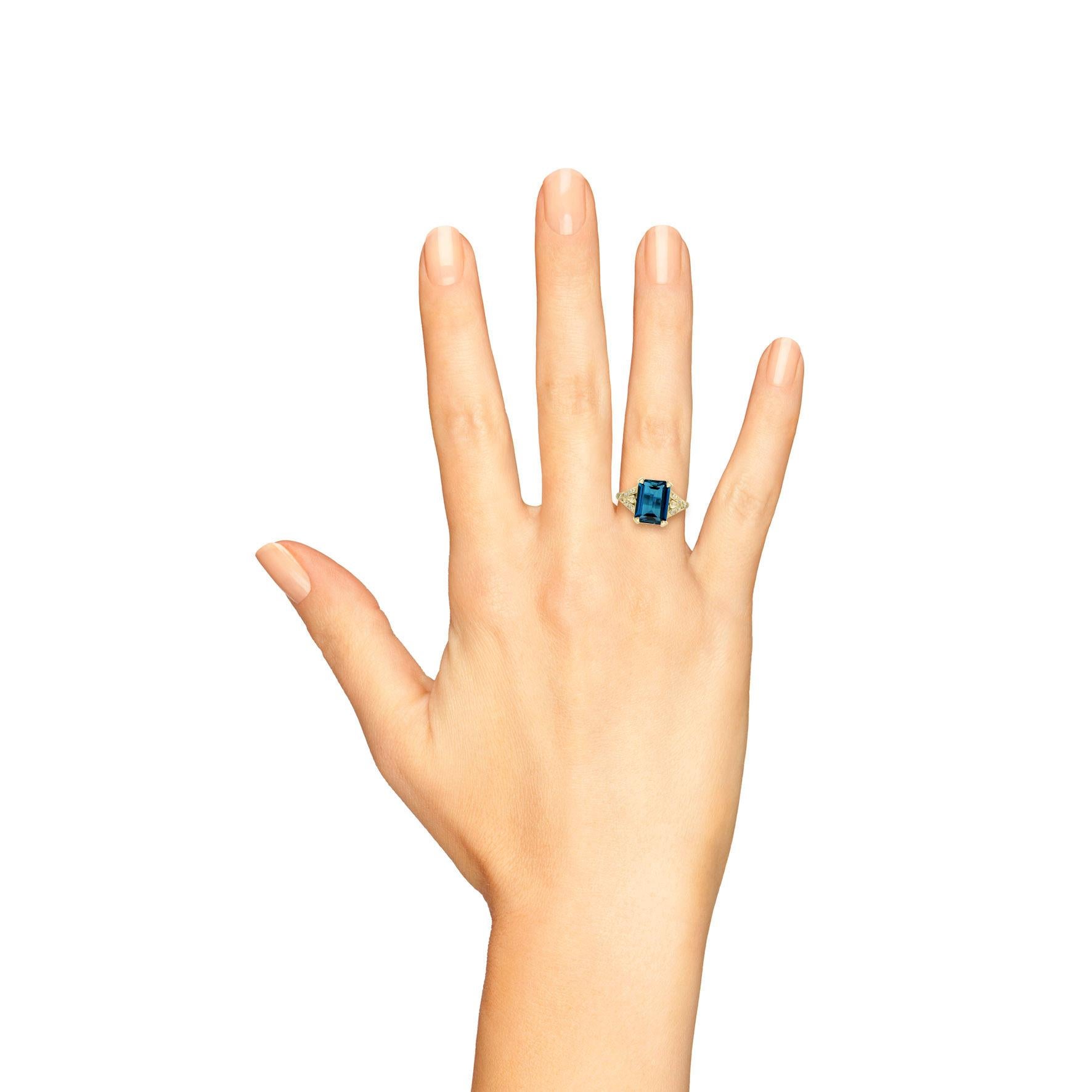 This spectacular London blue topaz Art Deco ring is a unique and glamorous vintage inspired piece. This ring features a beautiful emerald cut London blue topaz with a glittering white diamonds on its shoulders. Crafted in 14k yellow gold. It would