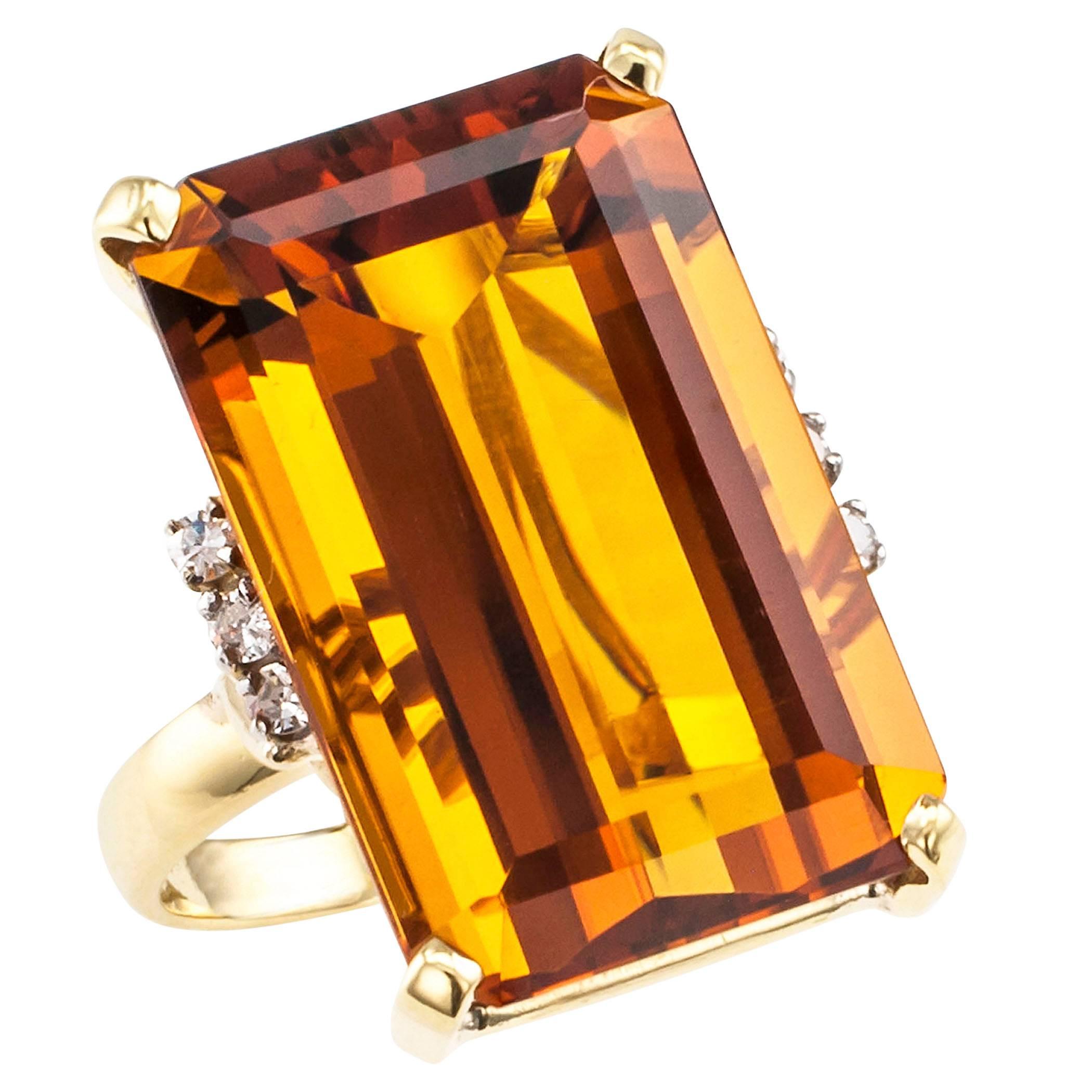 Emerald cut Madeira citrine diamond gold cocktail ring circa 1970. Centering upon an emerald-cut Madeira citrine weighing 23.91 carats, between shoulders set with six round diamonds totaling approximately 0.15 carat, mounted in 18-karat yellow gold.