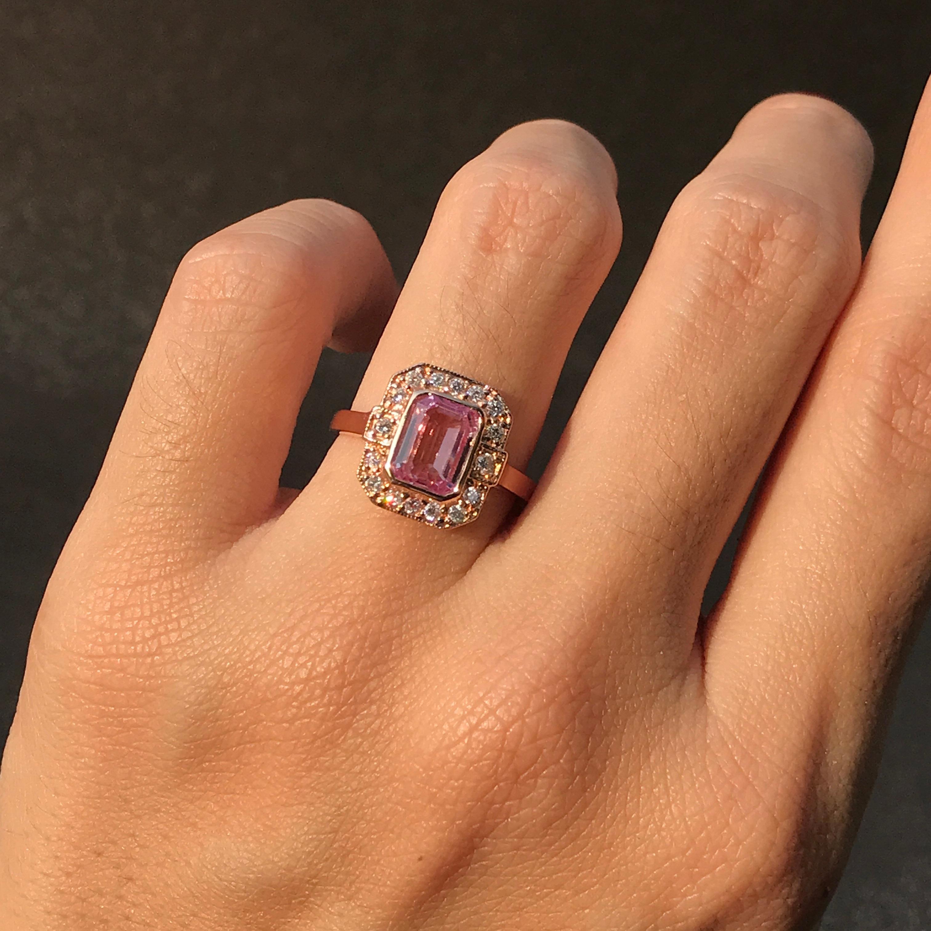 A gorgeous Art Deco inspired emerald cut pink sapphire is presented in classic Art Deco style. The glorious gemstone radiates from within a sparkling halo of bright round brilliant cut diamonds all set in18k rose gold.

Ring Information
Style: Art