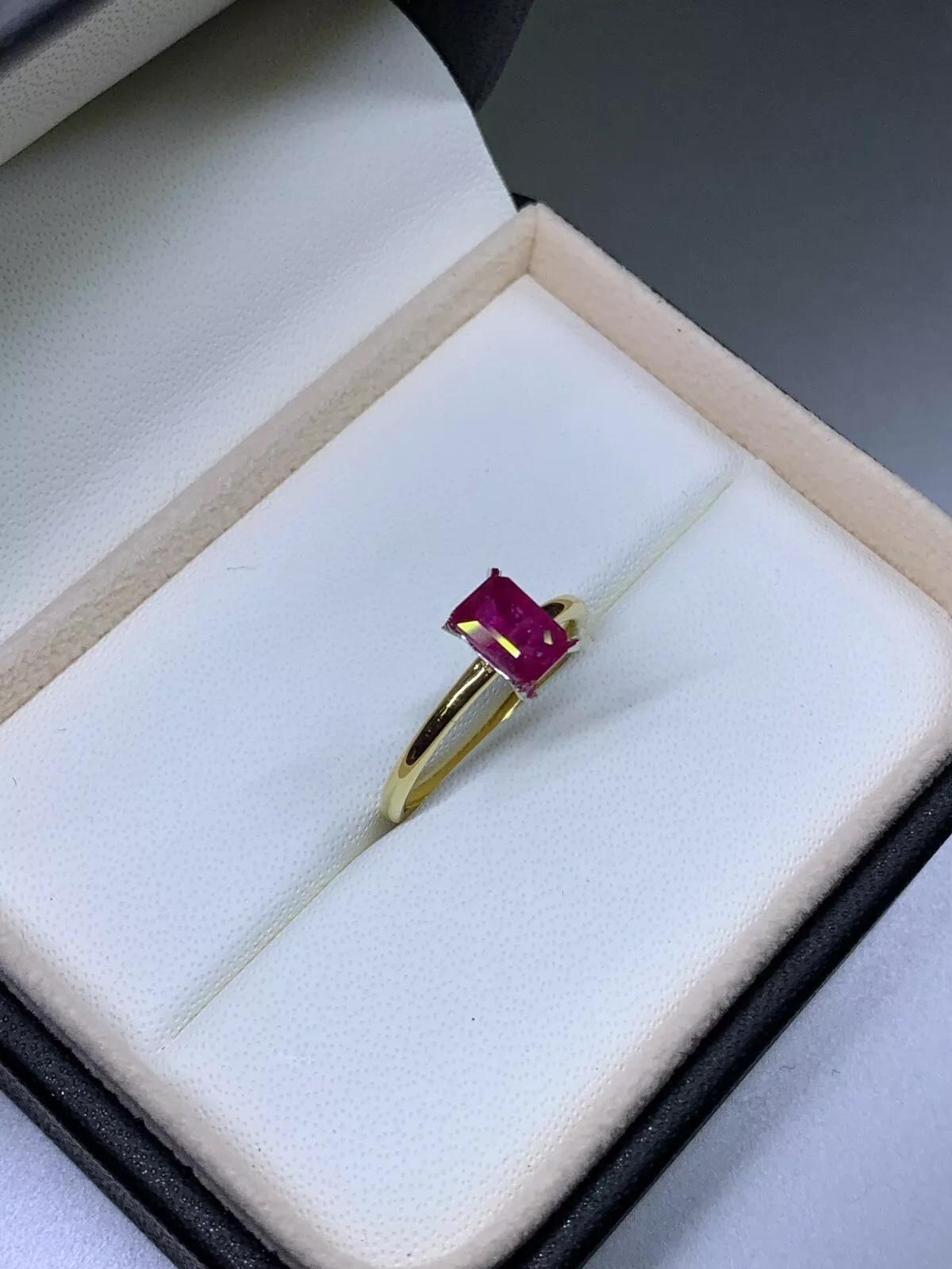 This stunning engagement ring is the perfect symbol of love and commitment. Crafted from 18ct yellow gold, it features a beautiful emerald cut ruby as the main stone, with additional rubies as secondary stones. The solitaire setting style ensures