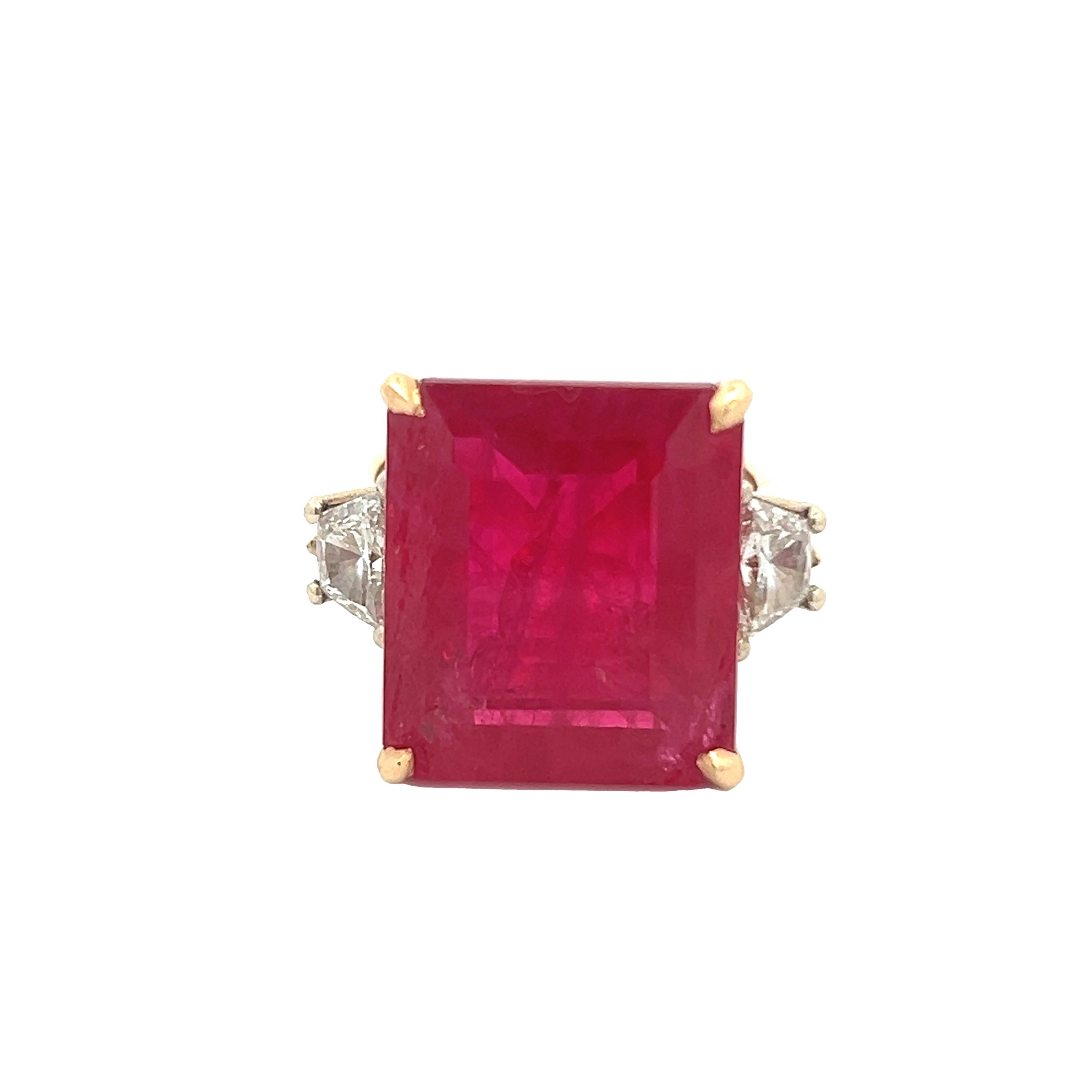 Entdecken Sie den Inbegriff von Raffinesse mit diesem bemerkenswerten 3-Stein-Mode-Ring aus 18 Karat Gelbgold, der Sie in seinen Bann zieht und beeindruckt. Sein Herzstück ist ein atemberaubender 24-karätiger Rubin im Smaragdschliff, der in sattem