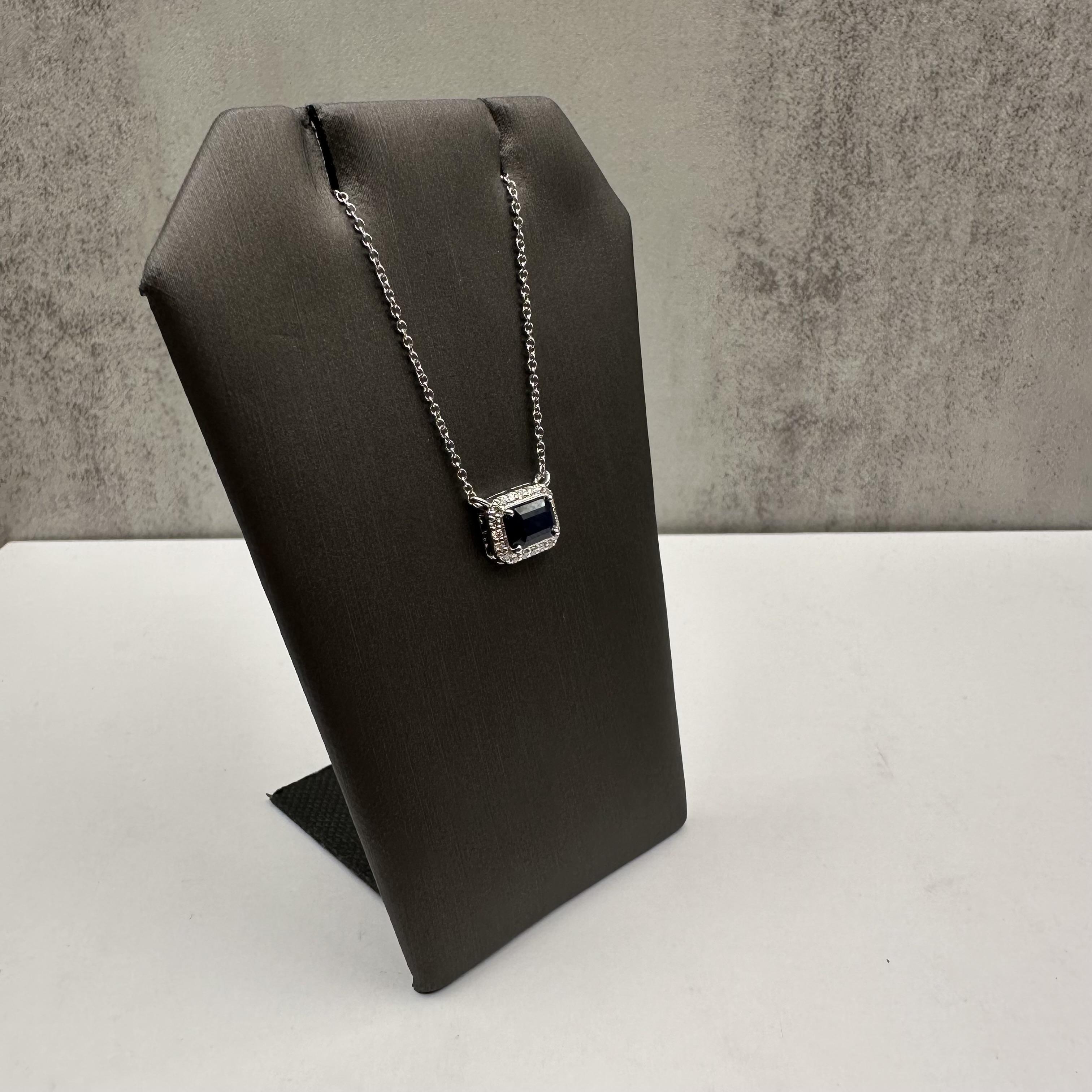 Aggiungi un tocco di eleganza alla tua collezione di gioielli con questa splendida collana di zaffiri e diamanti taglio smeraldo, realizzata in oro bianco 14 carati. Il centro è caratterizzato da uno zaffiro blu taglio smeraldo di 6,8x4,7 mm, che