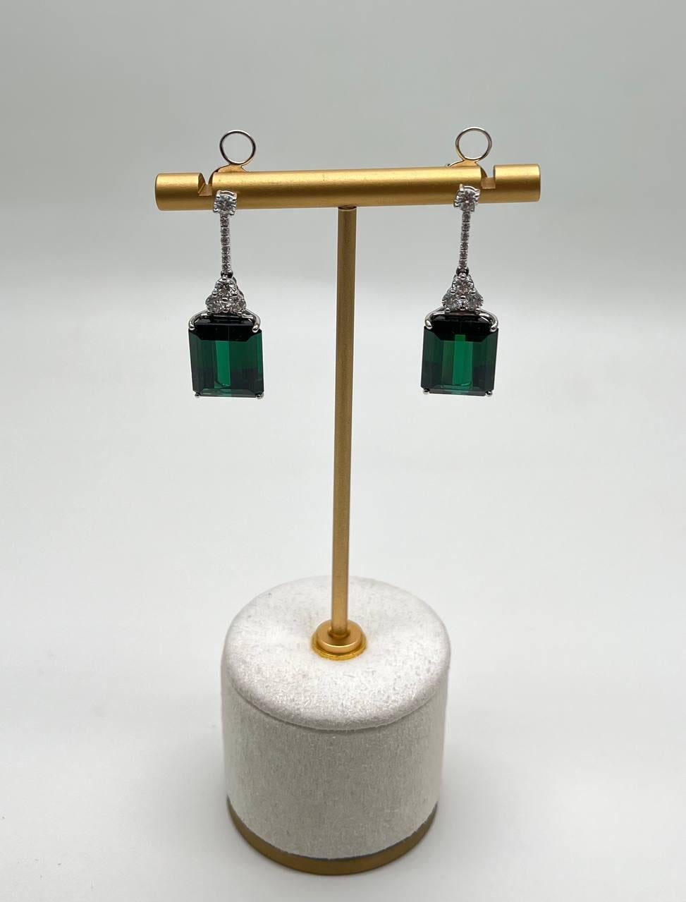Questa splendida coppia presenta un design sorprendente con tormaline rettangolari verde intenso, elegantemente incastonate in oro bianco massiccio 18 carati. Gli orecchini sono impreziositi da dettagli intricati sopra le gemme, che aggiungono un