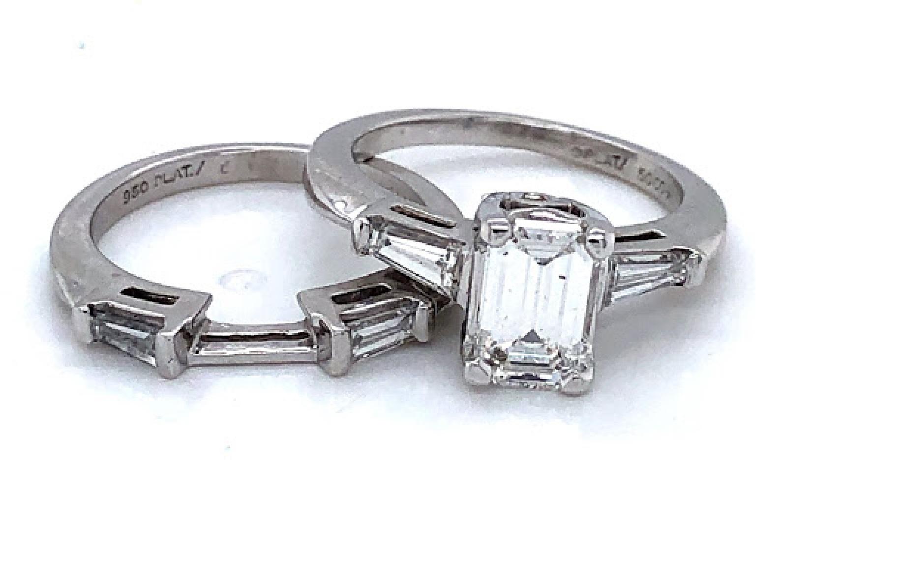 Platinum (stamped 0PLAT/5OCO*) three stone engagement ring, featuring a 7.26 mm by 4.51 mm emerald cut center stone. The Center stone weighs approximately 0.85 carat, is an H in color, a SI clarity, and is set into a four prong basket setting. On