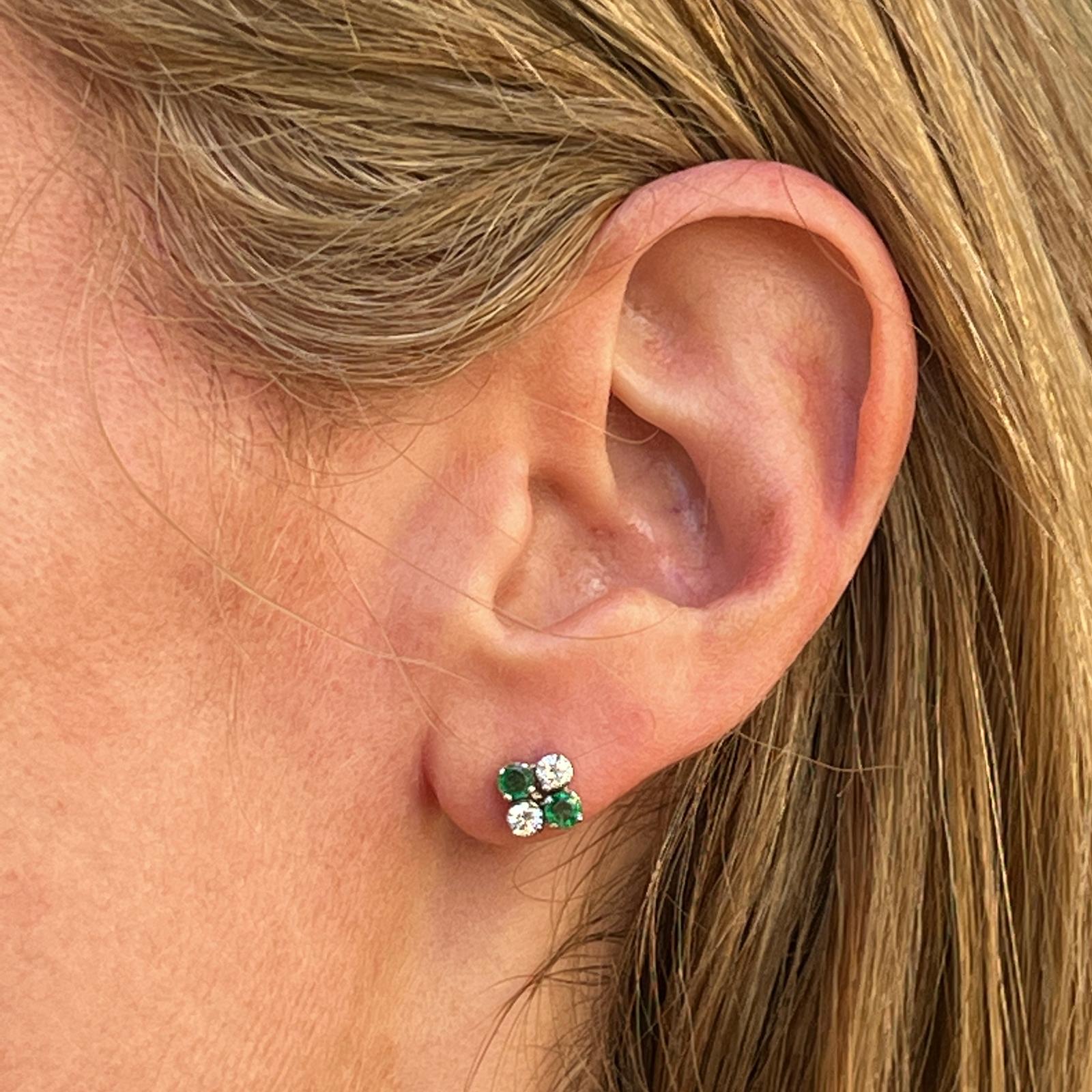 Diamond and emerald stud earrings crafted in 18 karat white gold. The studs feature 4 round natural emeralds and 4 round brilliant cut diamonds weighing approximately .40 carat total weight. The diamolnds are graded G-H color and VS2-SI1 clarity.