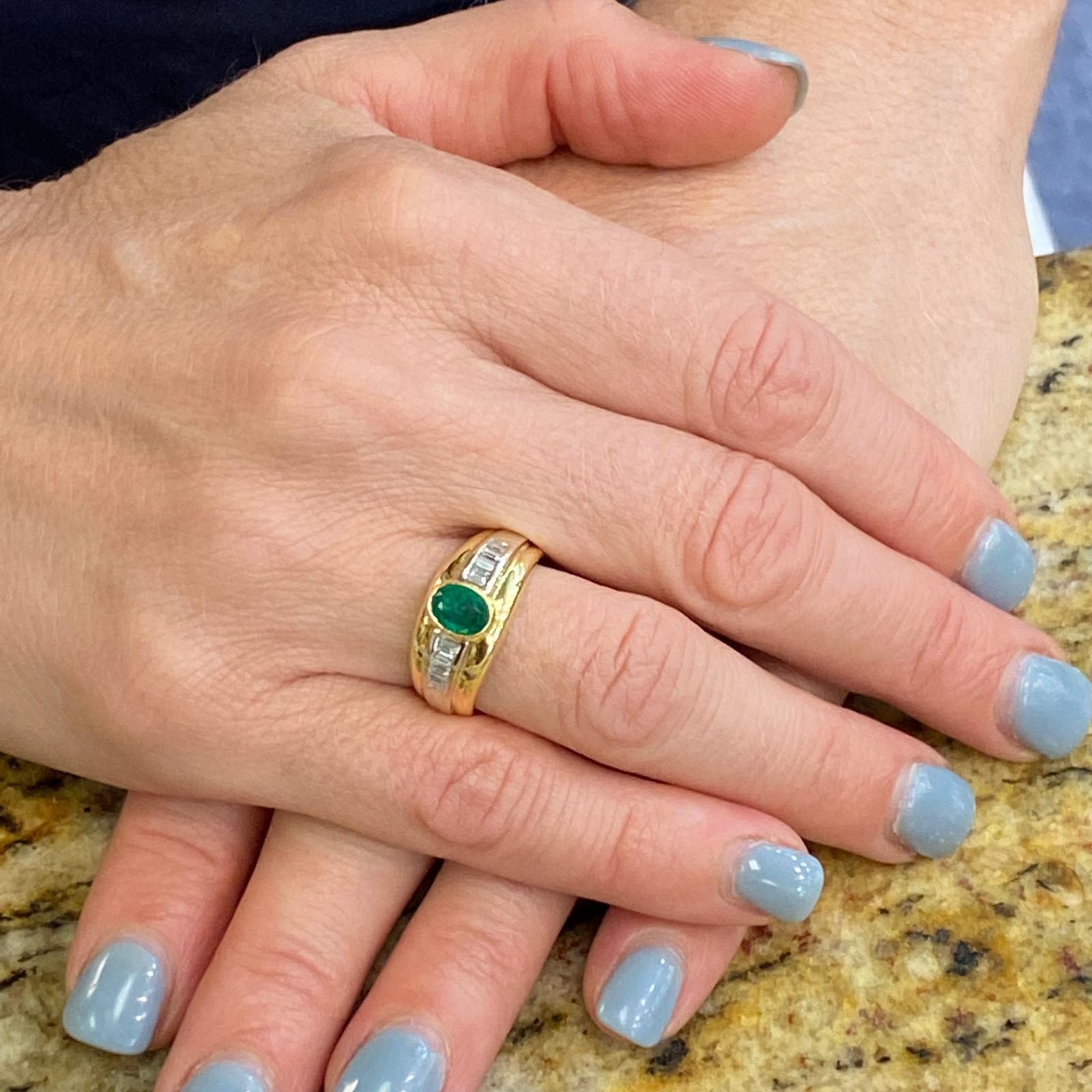 Beautiful emerald and diamond band ring fashioned in 18 karat yellow and white gold. The ring features an oval .50 carat deep green emerald and 8 baguette cut diamonds weighing .33 carat total weight. The diamonds are graded H-I color and VS