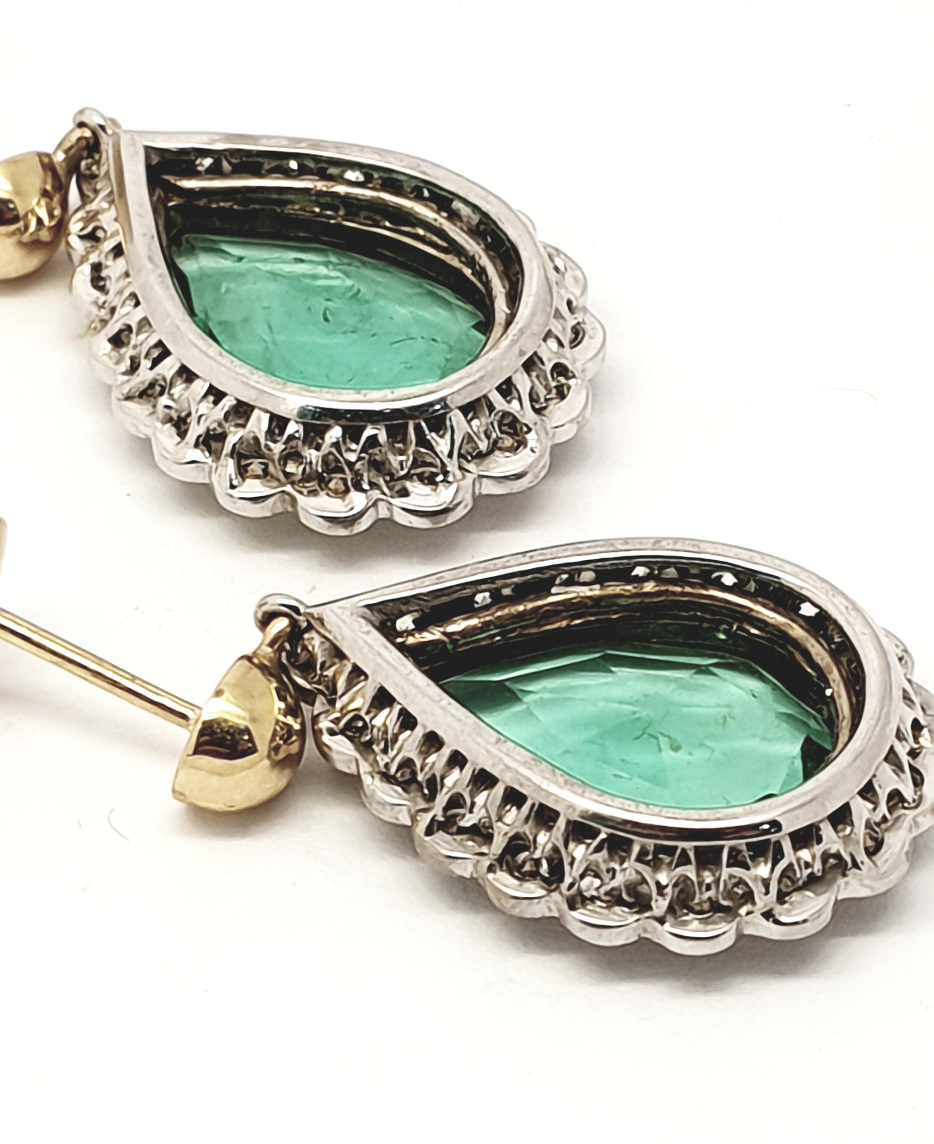 Emerald diamond cluster drop  earrings.Each  one set with one pear cut emerald in rubbed over setting in yellow gold.
This is surrounded by eighteen round brilliant cut diamonds set in white gold.
The back is hallmarked. Size of the emeralds 3 ct