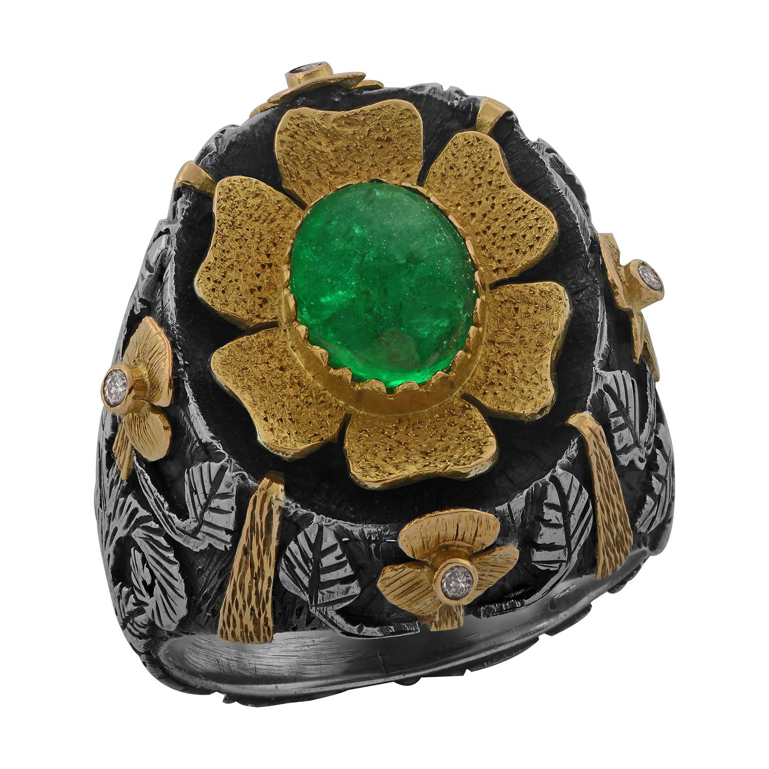 This striking one-of-a-kind emerald diamond cocktail ring has been handmade in our workshops. It has a central cabochon emerald which is set in 18k gold and is surrounded by full-cut diamonds also set in 18k gold. The shank is made in a mixture of