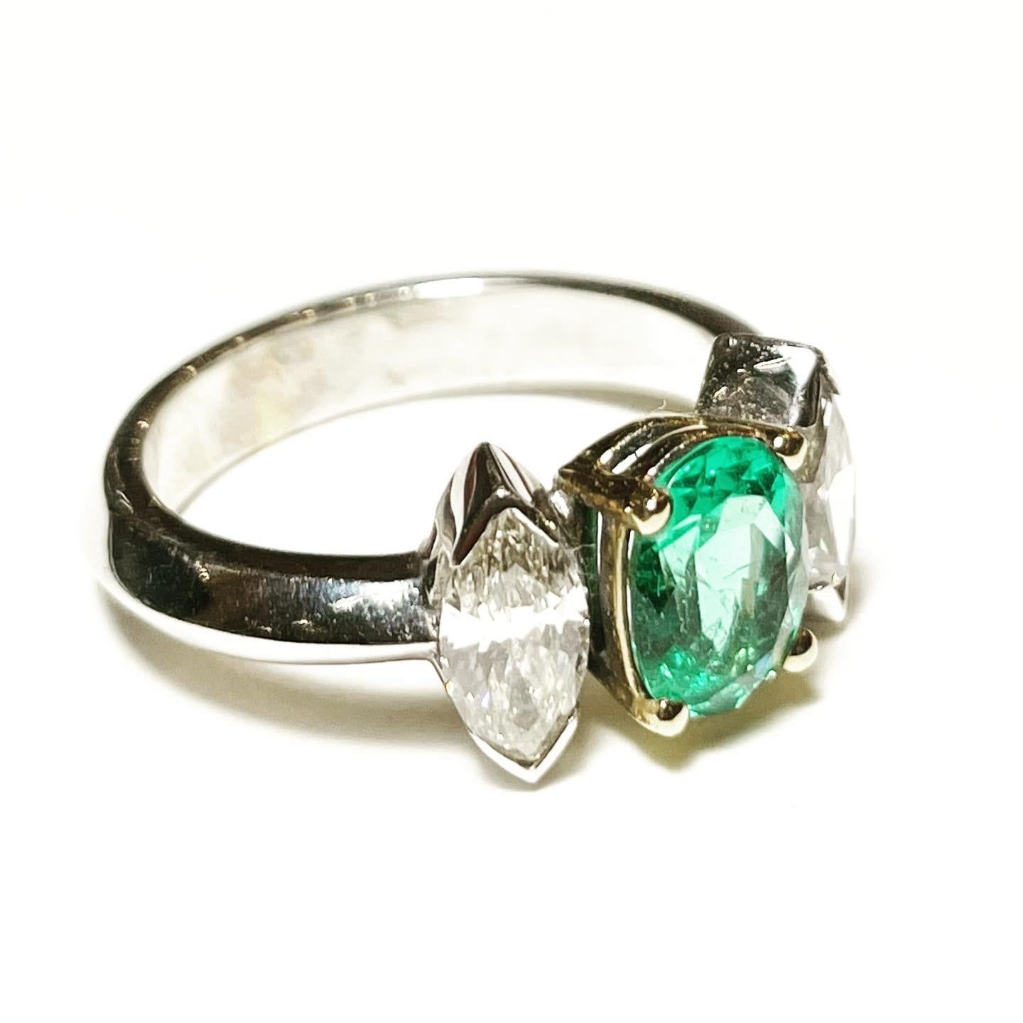 This classic three-stone engagement ring is crafted in 18K white gold.
At the centre of this three stone ring there is a gorgeous oval cut emerald  and sat either side is a bright sparkling navette diamond. The oval cut emerald weights 1.72 carat