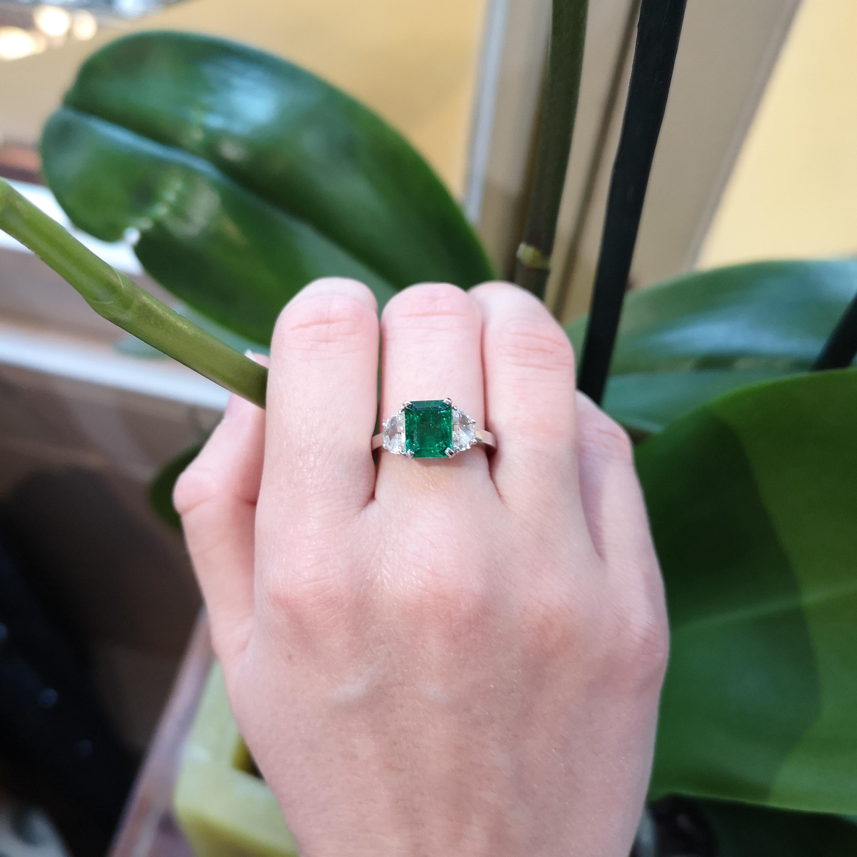 A modern emerald and diamond ring, set with a 2.00ct emerald-cut emerald, in a four claw setting, with a pair of half moon diamonds set in the shoulders, in claw settings, mounted in platinum, made in our London workshop, Hallmarked for